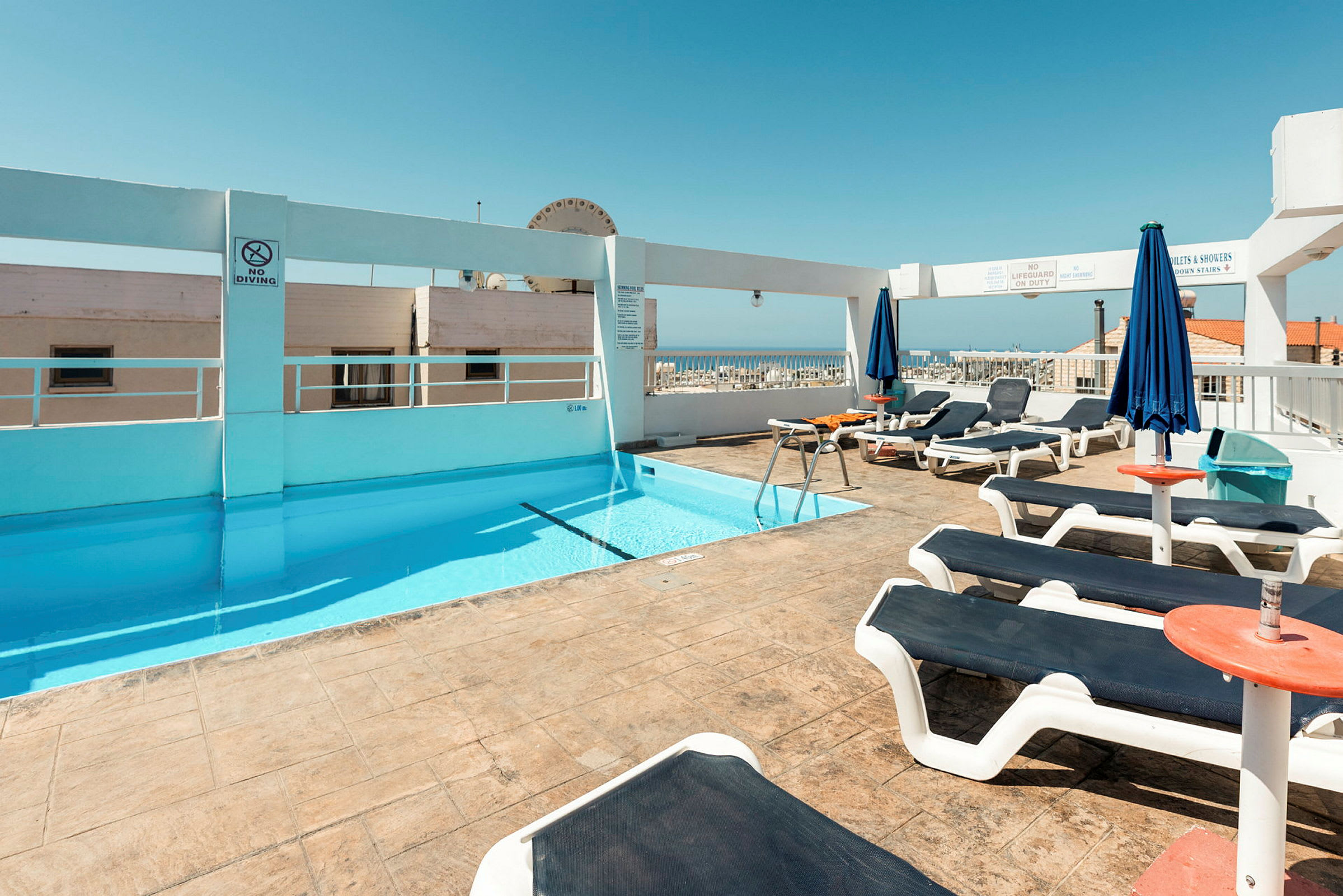 En tagterrasse med en pool og solsenge under en klar blå himmel. (AI-genereret tekst)