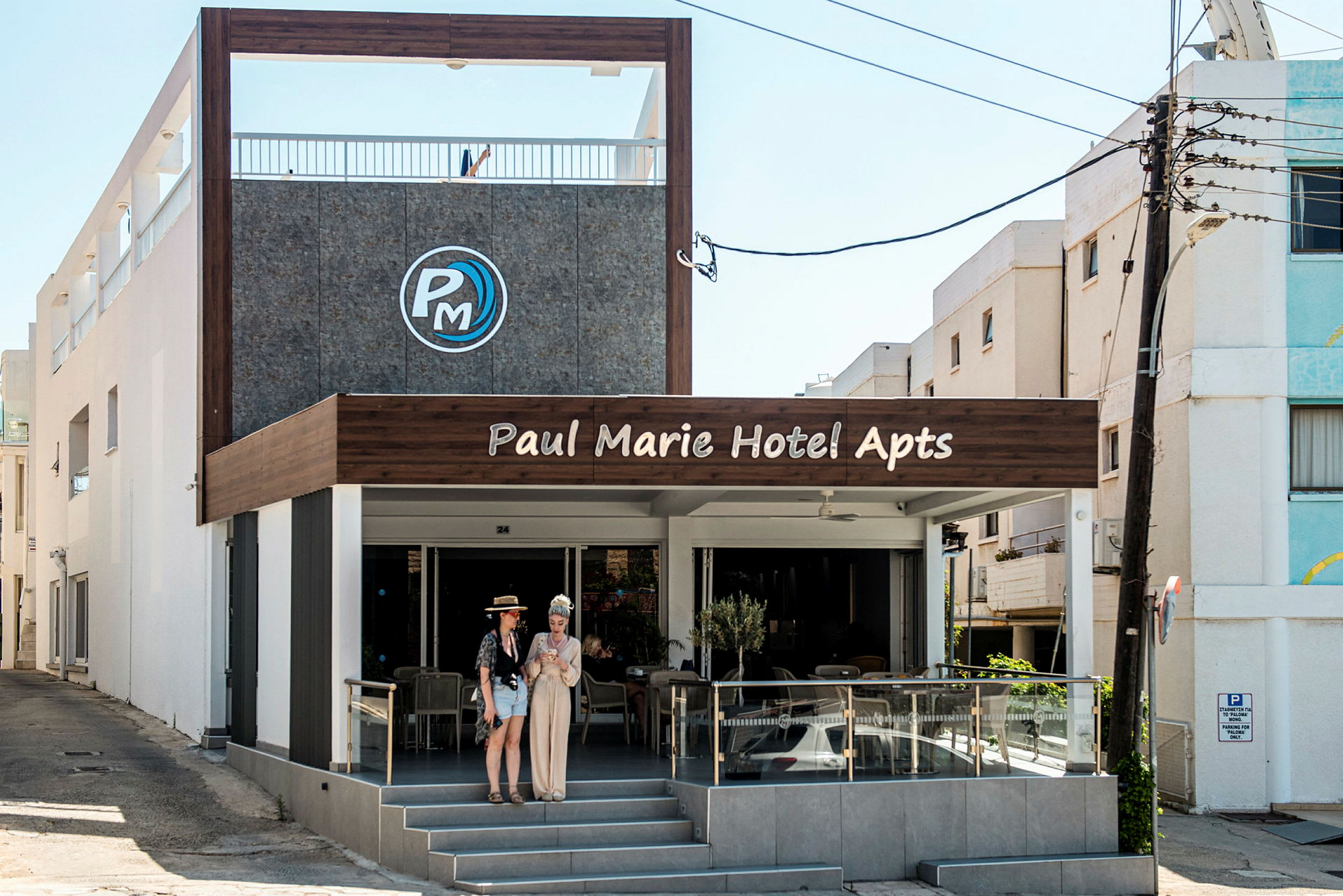 Forsiden af Paul Marie Hotel Apartments med udendørs servering og indgang. (AI-genereret tekst)