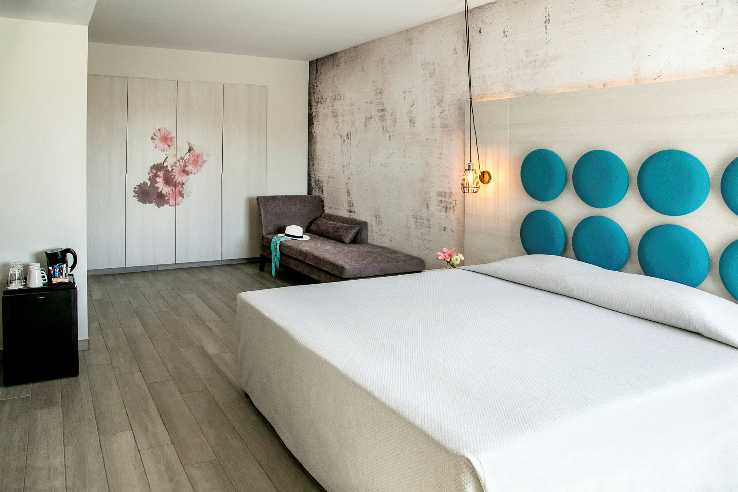 Et lyst hotelværelse med en stor seng, en sofa og et skab dekoreret med blomster. (AI-genereret tekst)