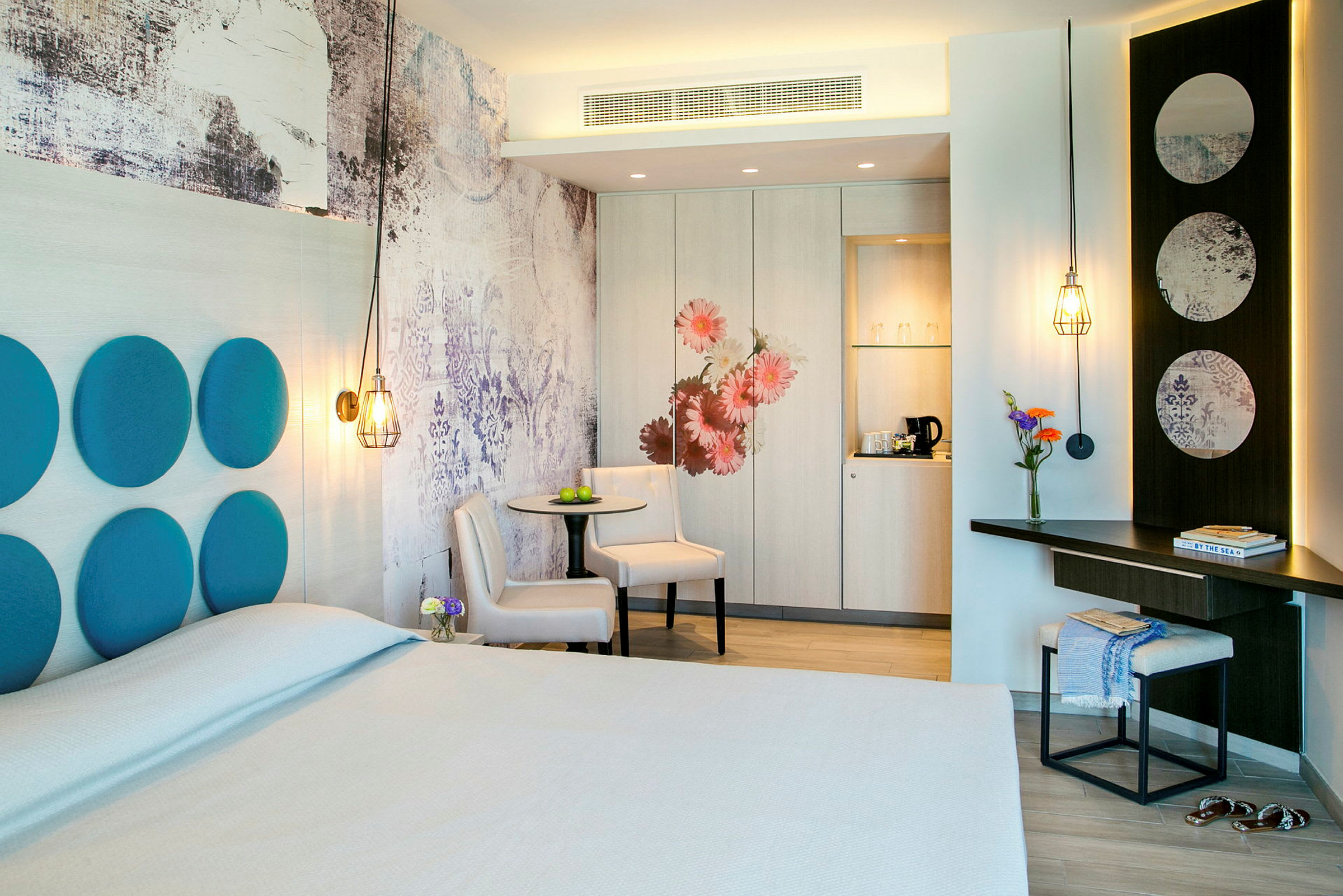 Et hotelværelse med moderne design, herunder en dobbeltseng, bord med stole og individuelle designdetaljer som dekorative paneler og belysning. (AI-genereret tekst)