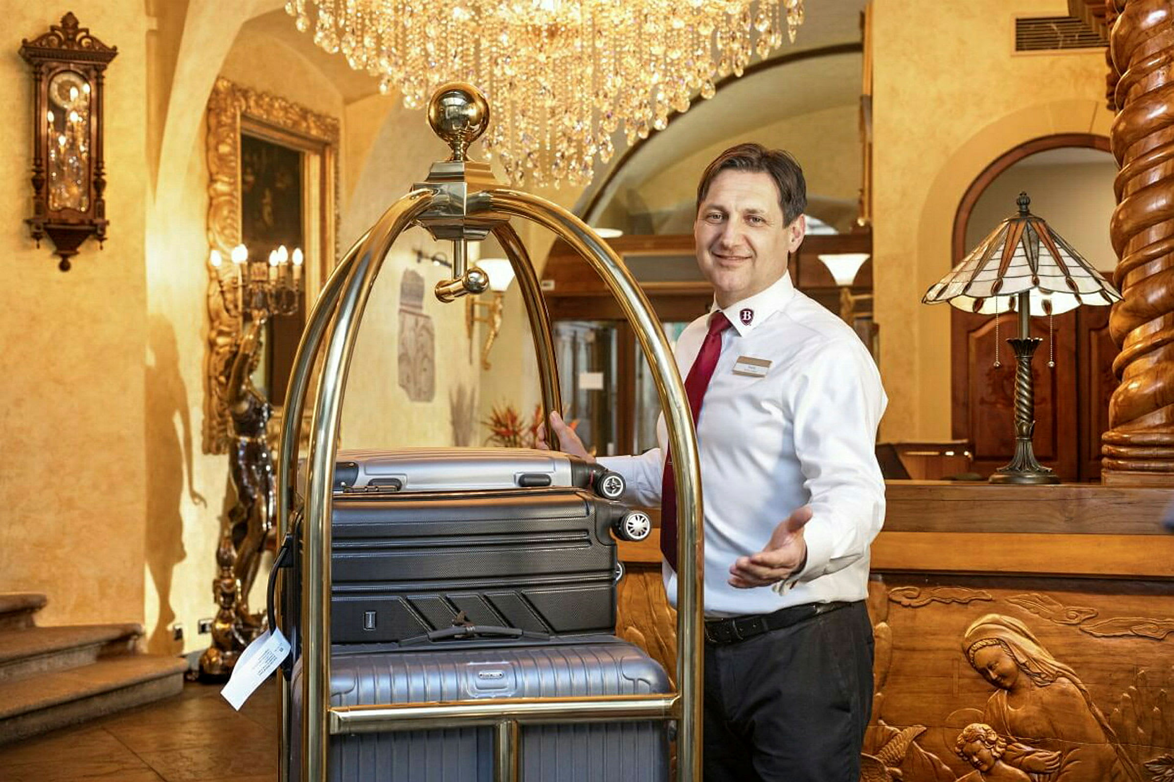 En hotelansat ved en reception med kufferter på en bagagevogn. (AI-genereret tekst)