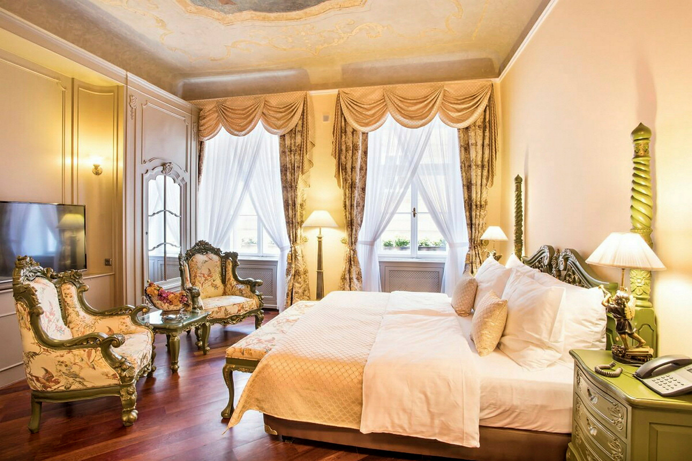 Et elegant hotelværelse med seng, to lænestole og et sofabord. Vinduer med gardiner og dæmpet belysning pryder rummet. (AI-genereret tekst)