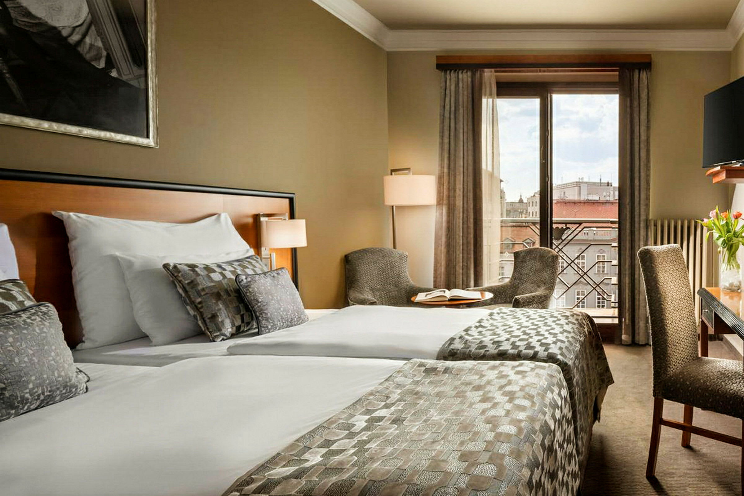 Hotelværelse med to senge, siddepladser og udsigt over byen. (AI-genereret tekst)