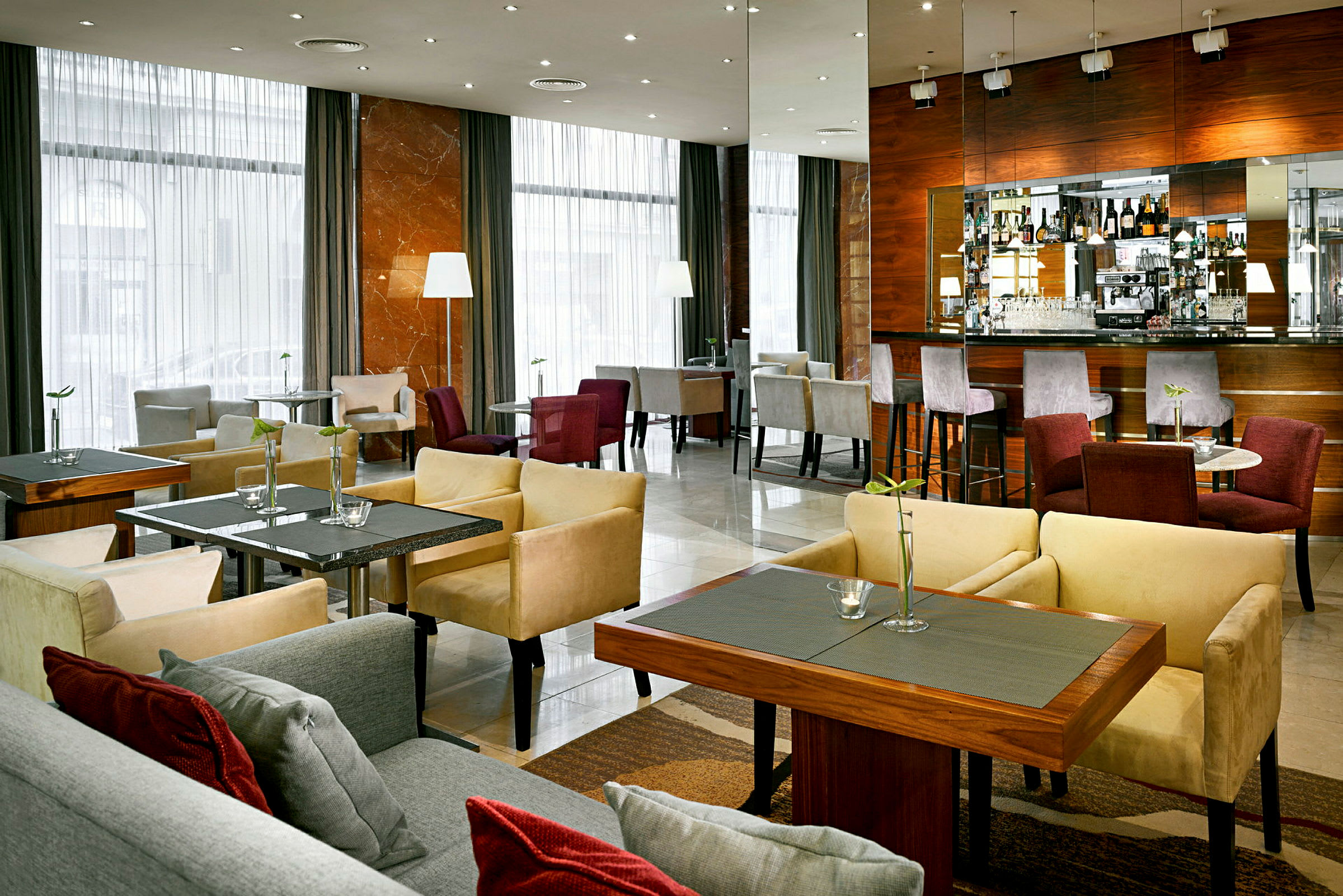En moderne hotellbar med siddepladser og borde samt en bardisk med stole. (AI-genereret tekst)