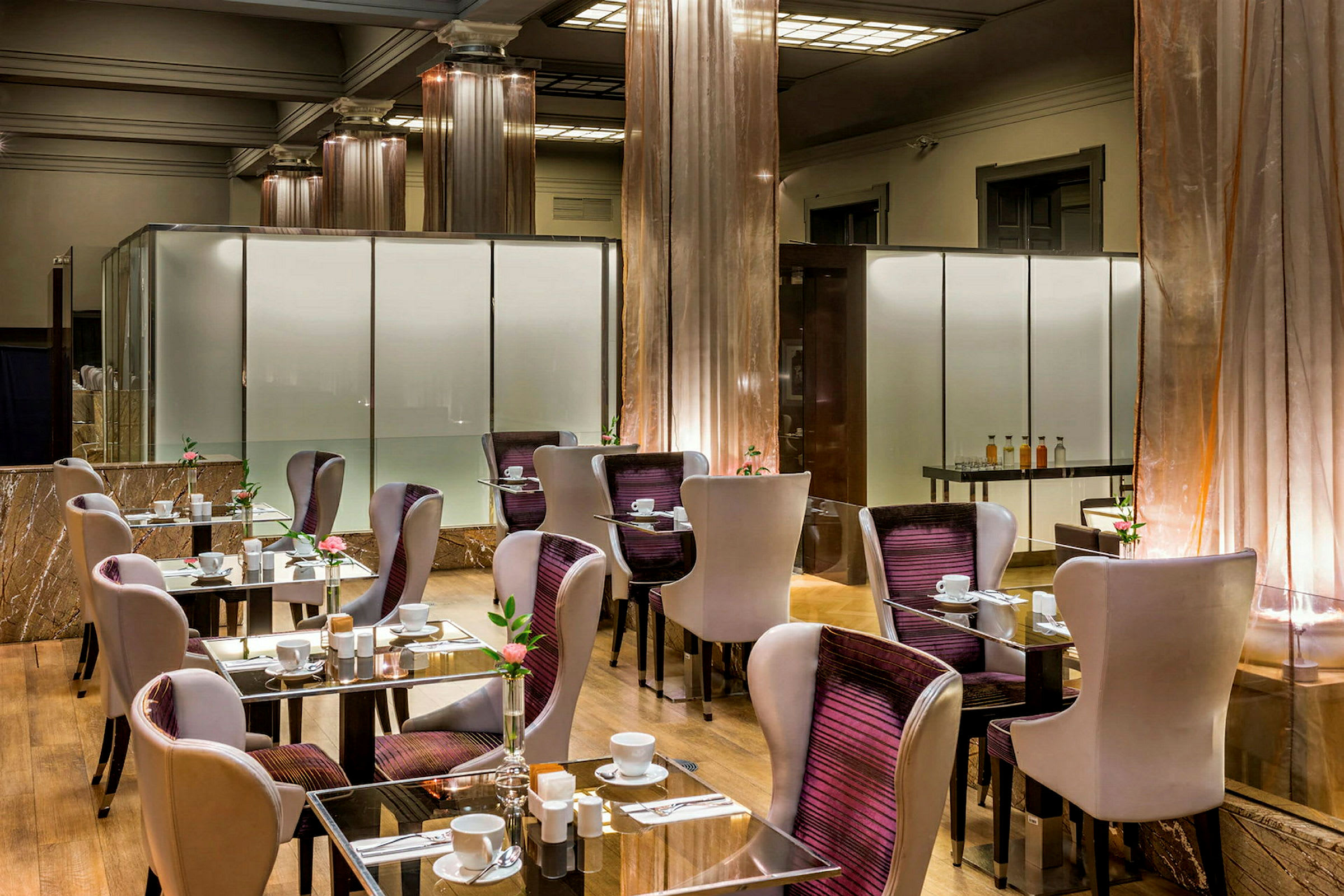 Moderne restaurant med borde og stole. Glasborde med opdækning og blomsterdekorationer. (AI-genereret tekst)