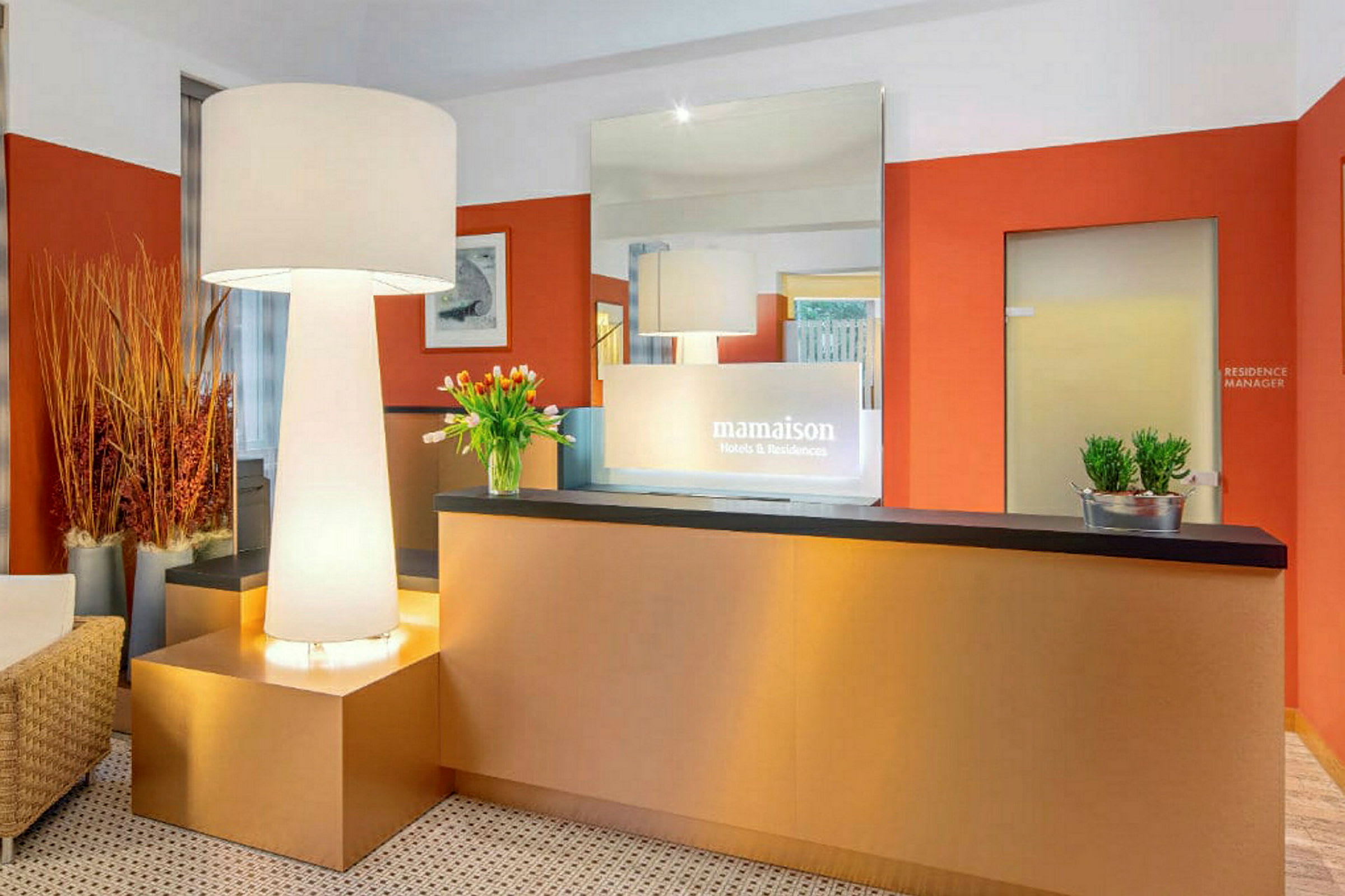 Receptionområde med et moderne indrettet bord, en stor gulvlampe og dekorationer som blomster og planter. (AI-genereret tekst)