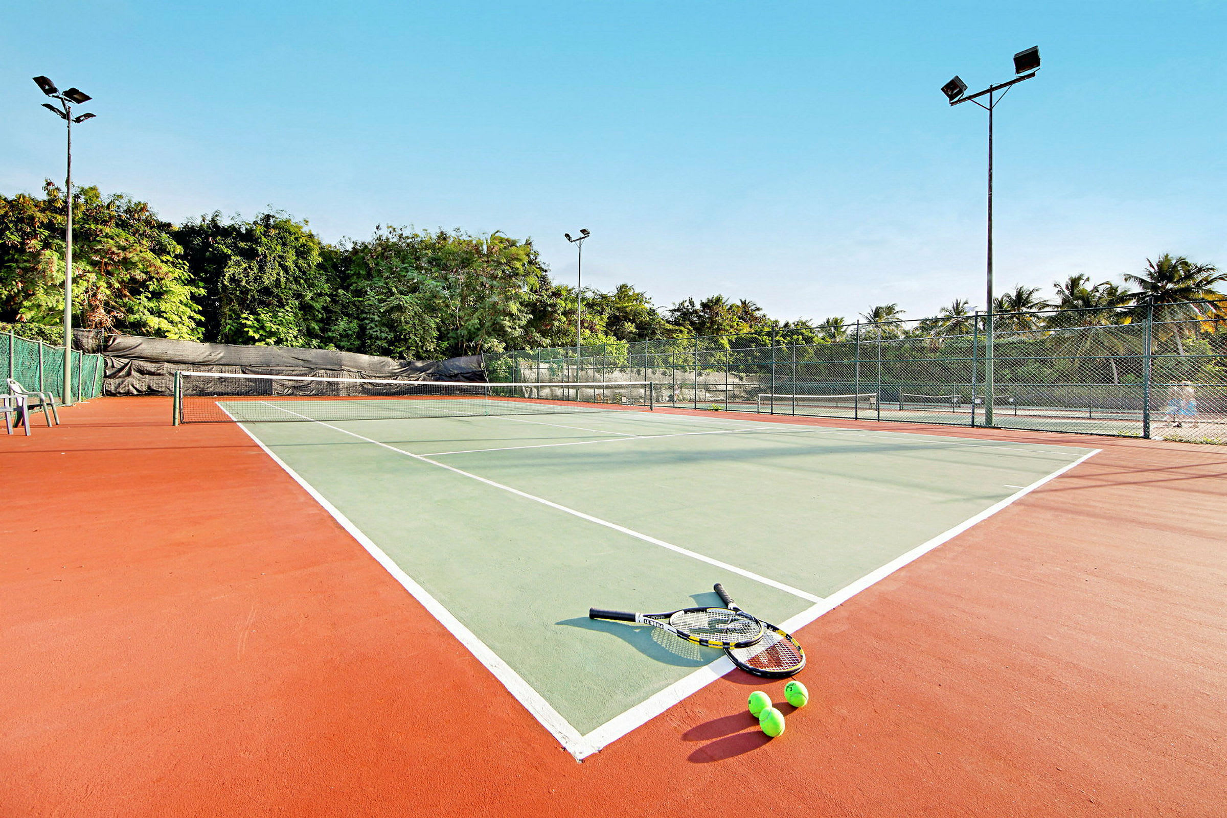 En tennisbane med ketchere og bolde liggende på jorden. (AI-genereret tekst)