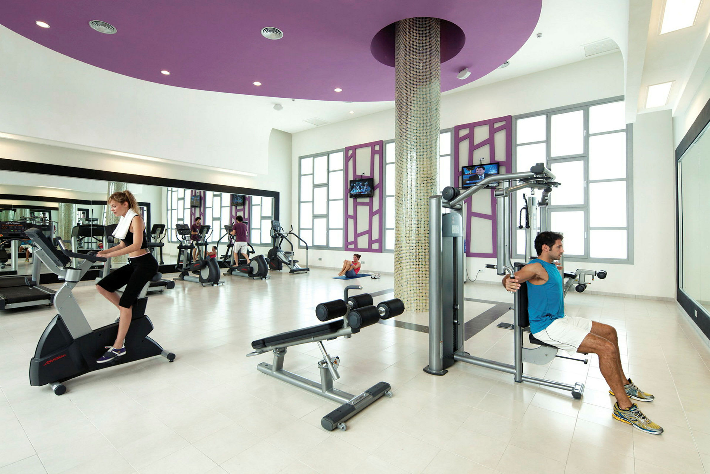Et fitnesscenter med træningsmaskiner og personer, der træner. (AI-genereret tekst)