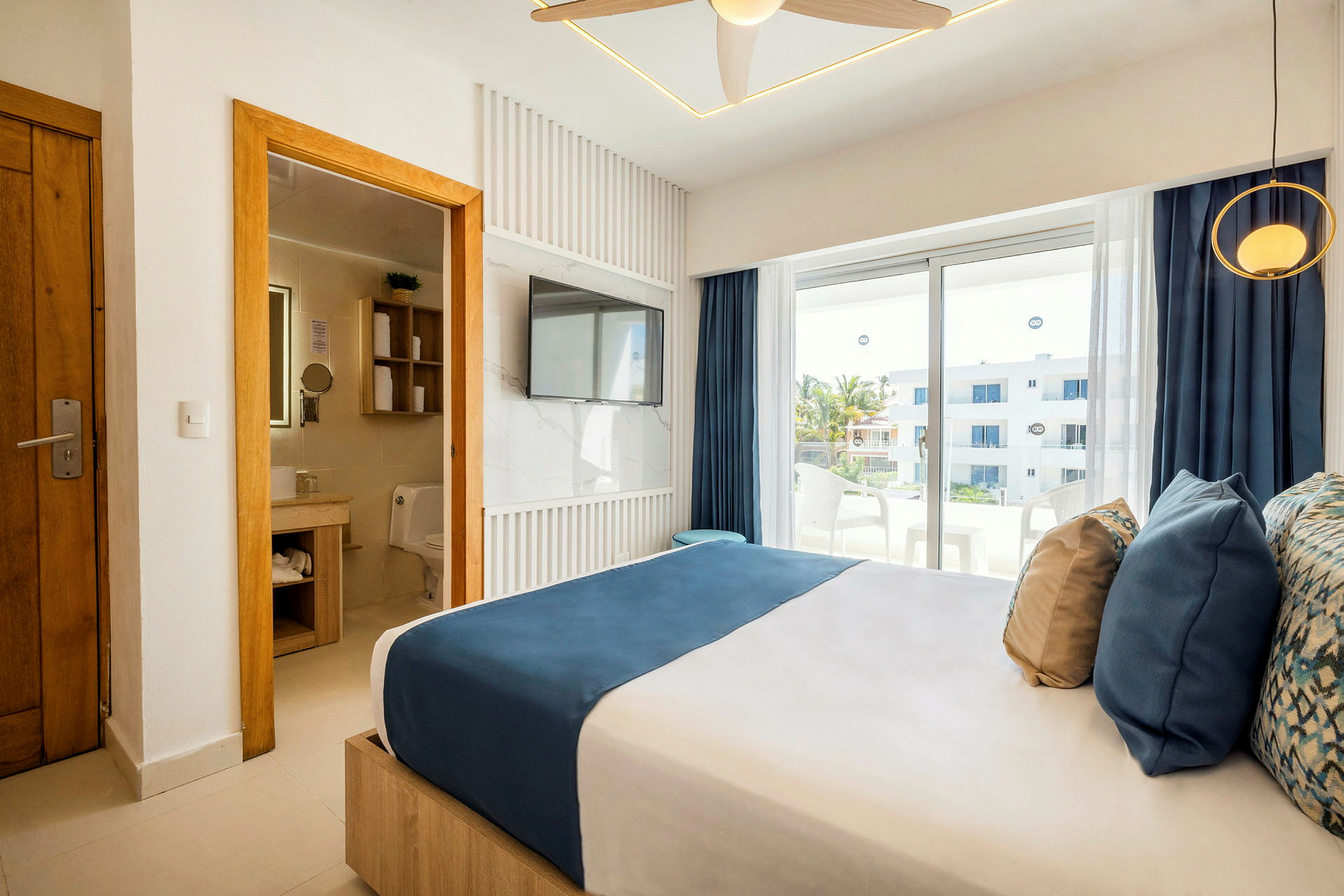 Et moderne hotelværelse med en dobbeltseng, badeværelse ved siden af til venstre og vindue ud til en balkon. (AI-genereret tekst)