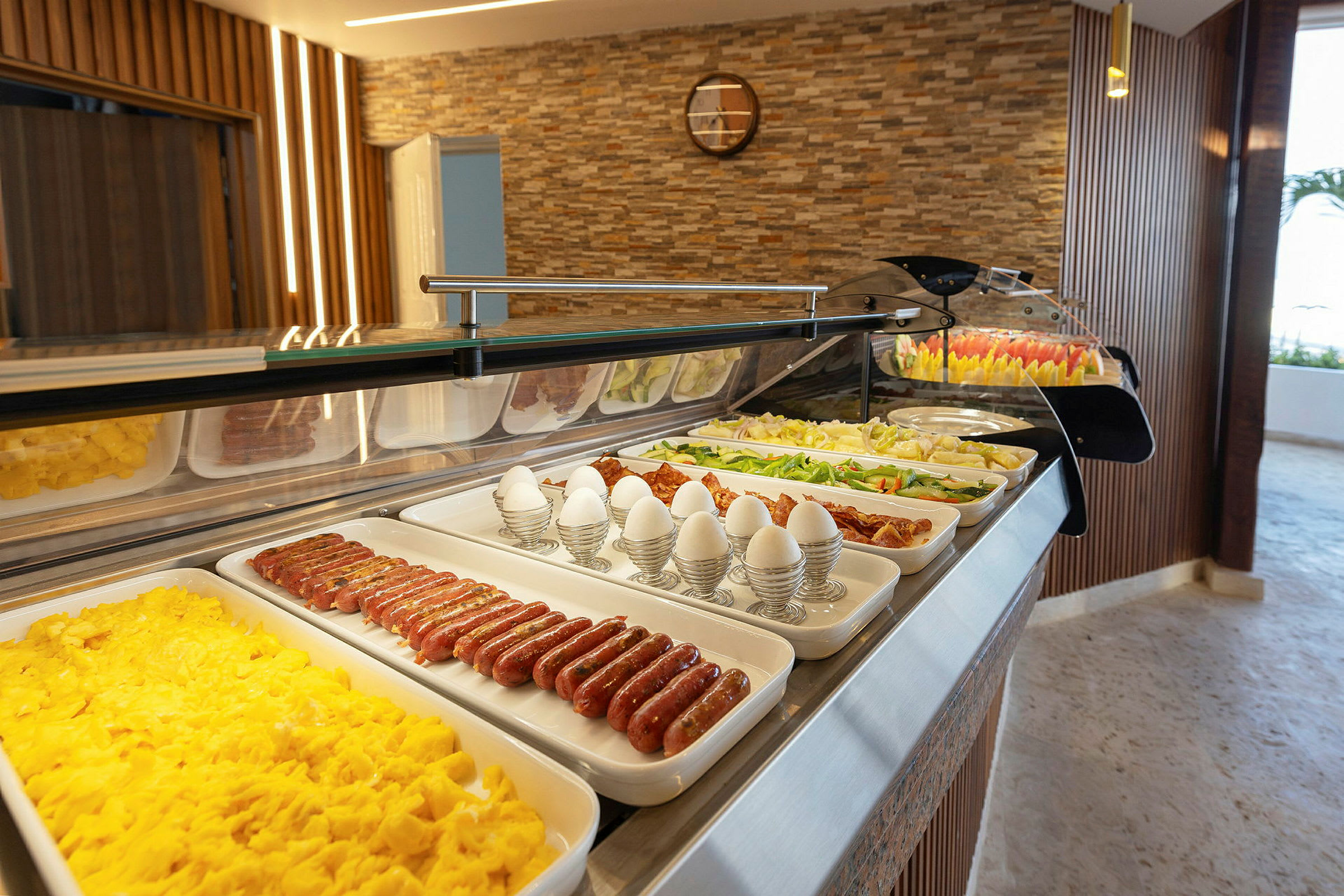 En buffet med morgenmadsmad som æg, pølser og grøntsager. (AI-genereret tekst)