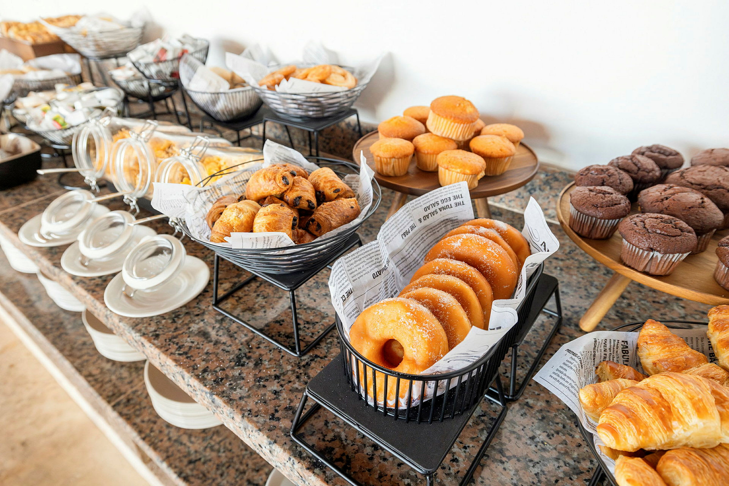 En buffet med forskellige bagværk som muffins, croissanter og donuts. (AI-genereret tekst)
