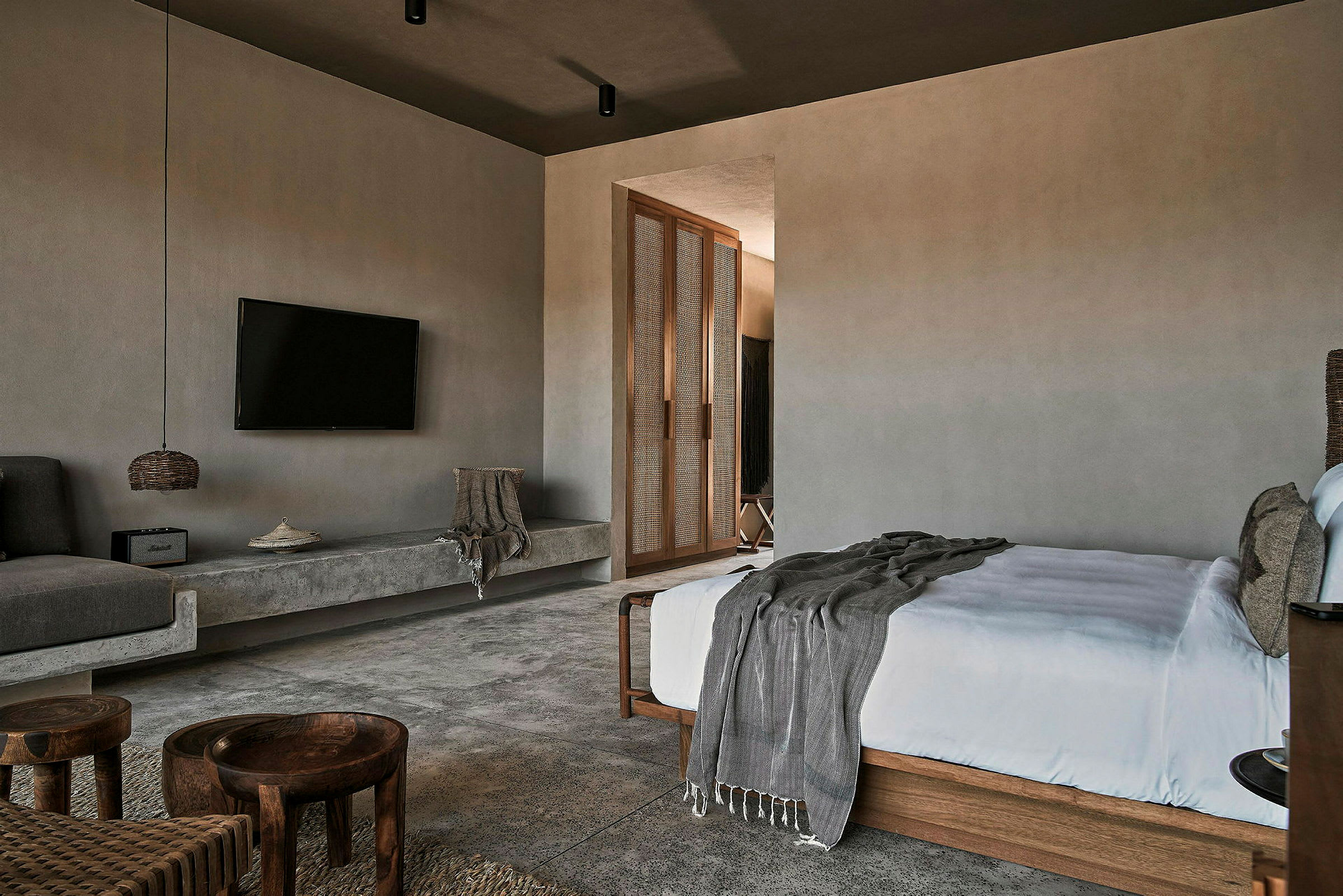 Et moderne designet hotelværelse med TV, seng, sofaområde og indgang til en anden del af værelset. (AI-genereret tekst)