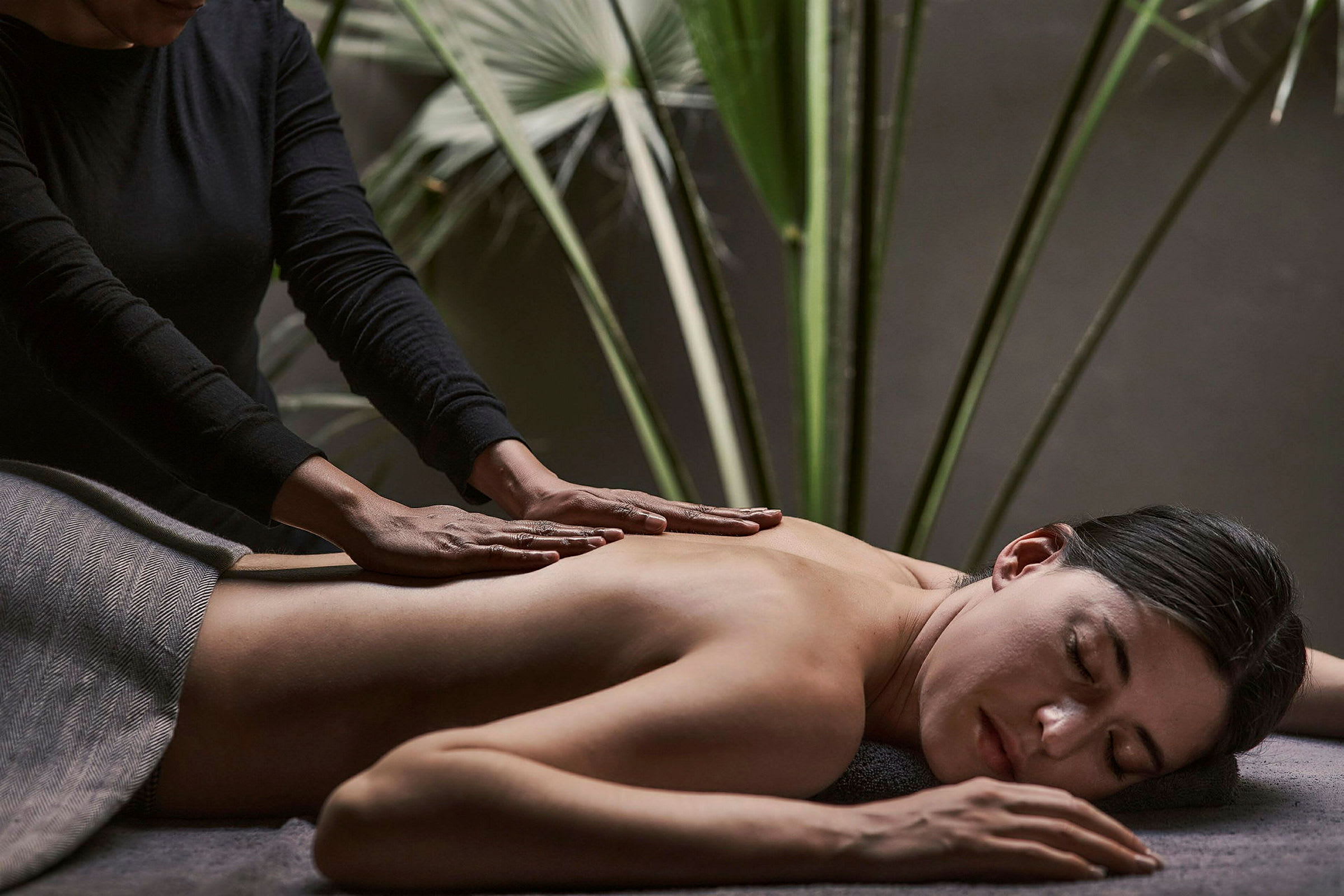 En person får en rygmassage med grønne planter i baggrunden. (AI-genereret tekst)