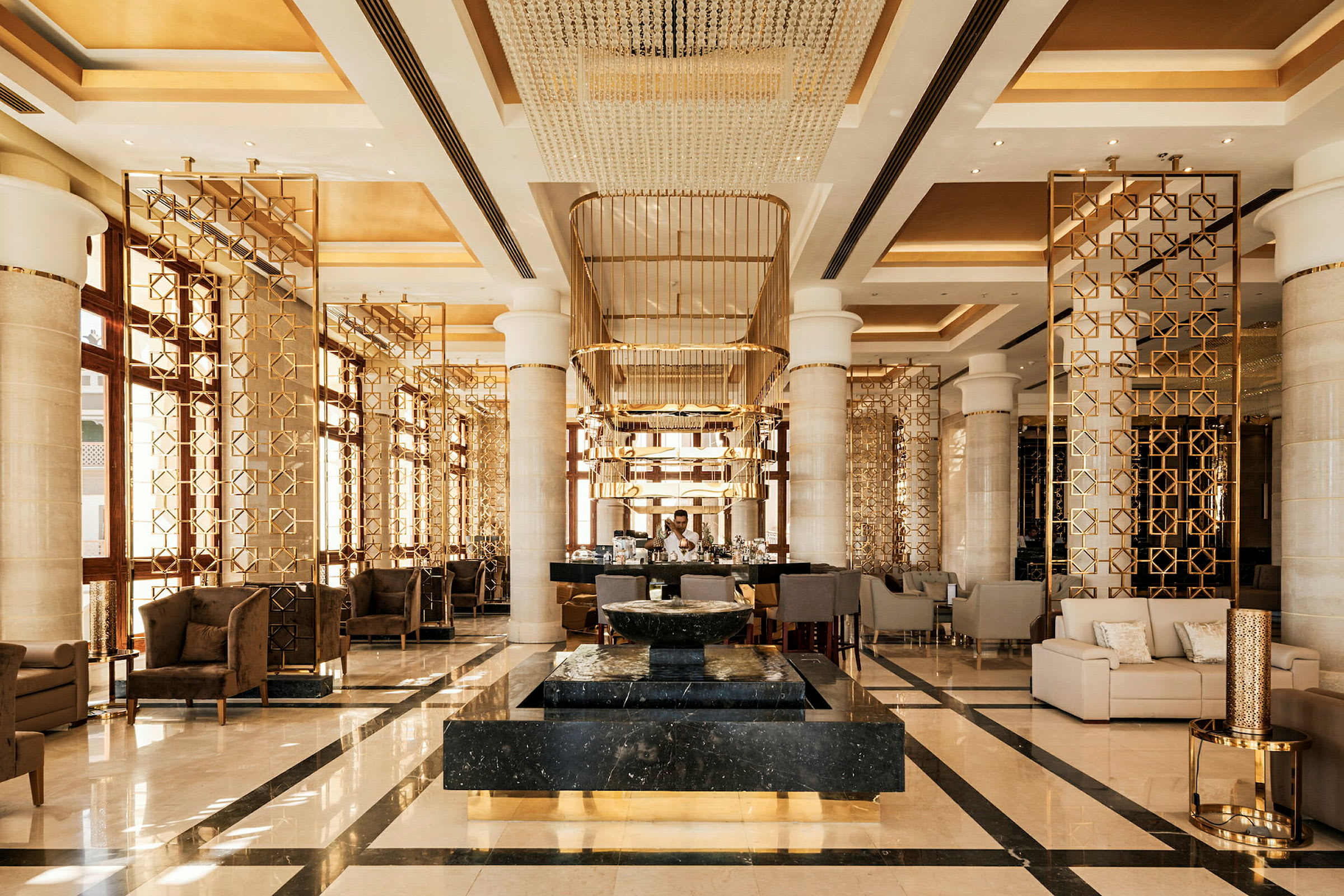 En elegant hotellobby med moderne møbler, guldfarvede dekorationer og et marmordekoration i centrum. (AI-genereret tekst)