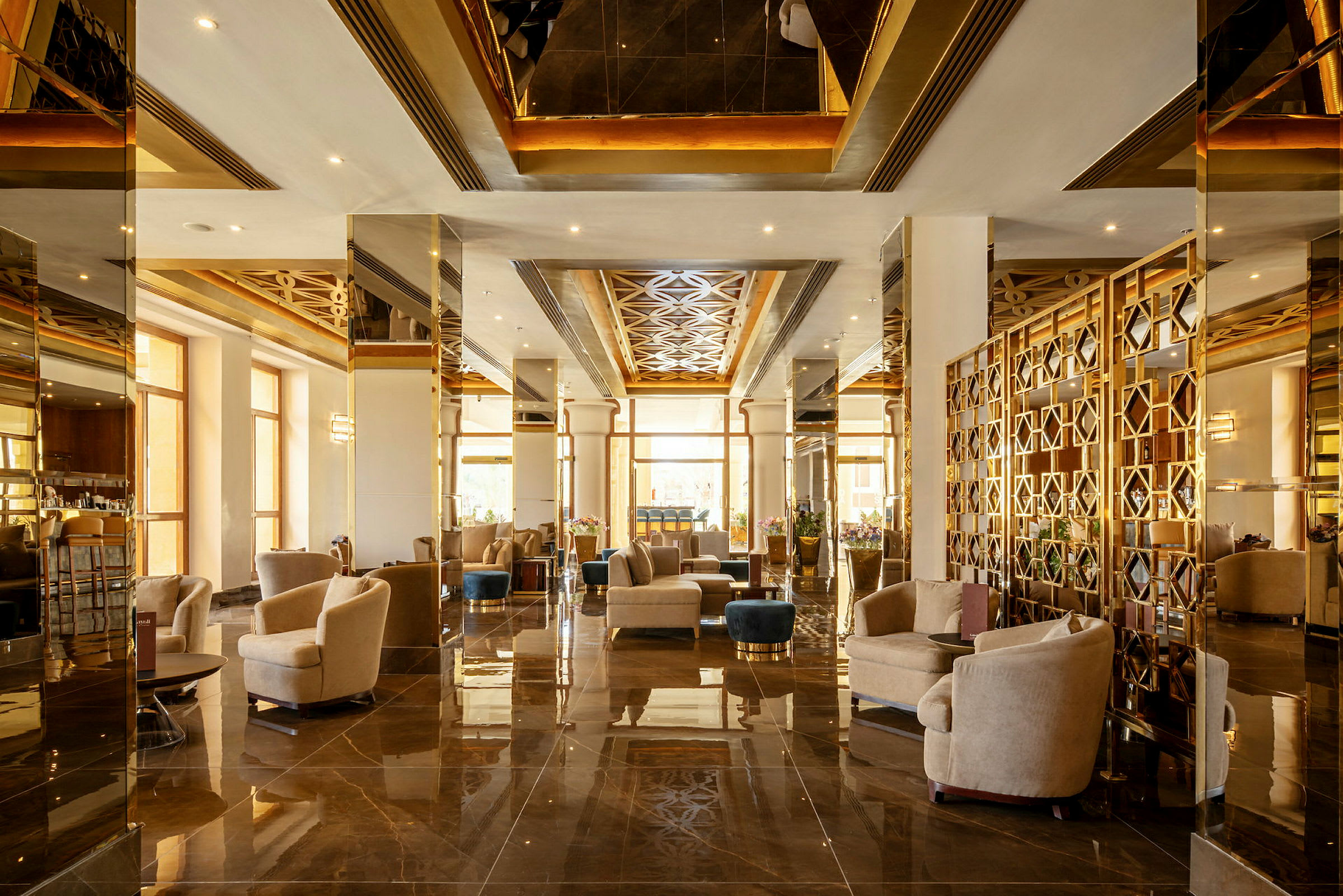 Elegant hotellobby med siddegrupper, dekoreret med spejle og gulddetaljer. (AI-genereret tekst)