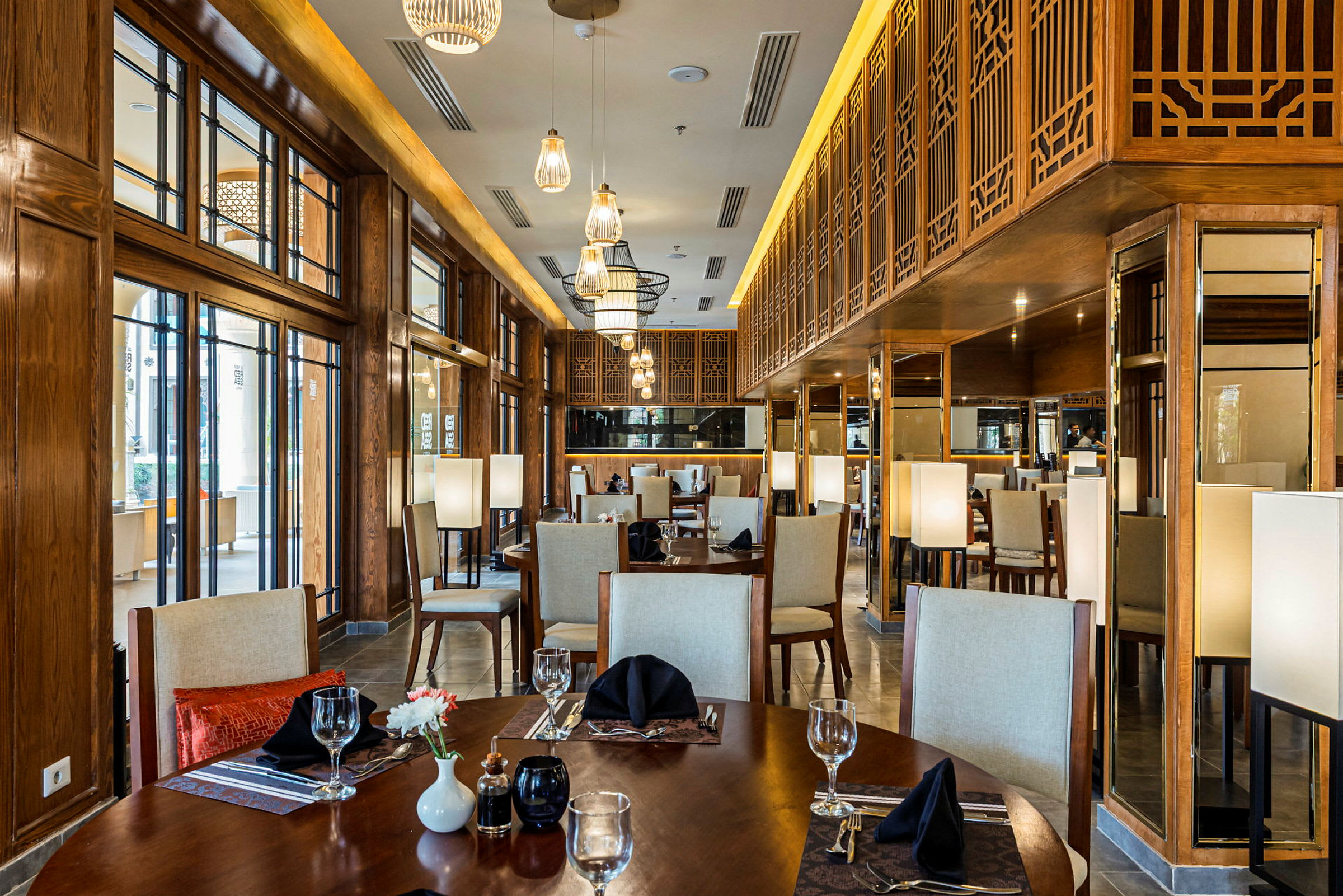 Billede af en elegant restaurant med træinteriør, designlamper og dækkede borde. (AI-genereret tekst)