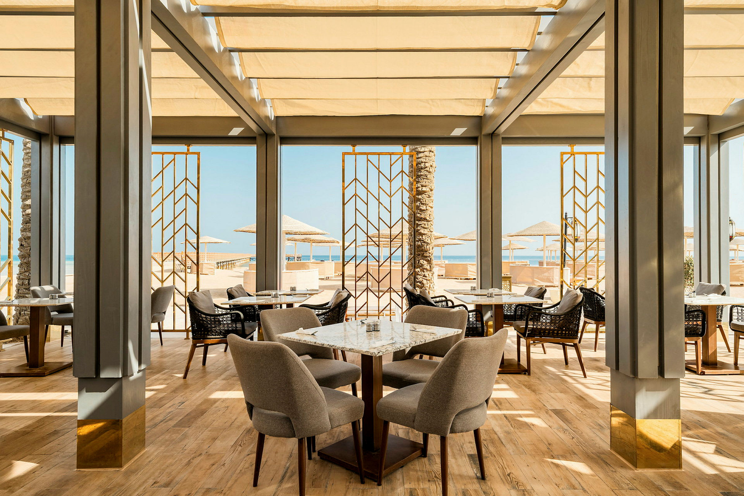En elegant restaurant med store vinduer der vender ud mod stranden og havudsigten (AI-genereret tekst)