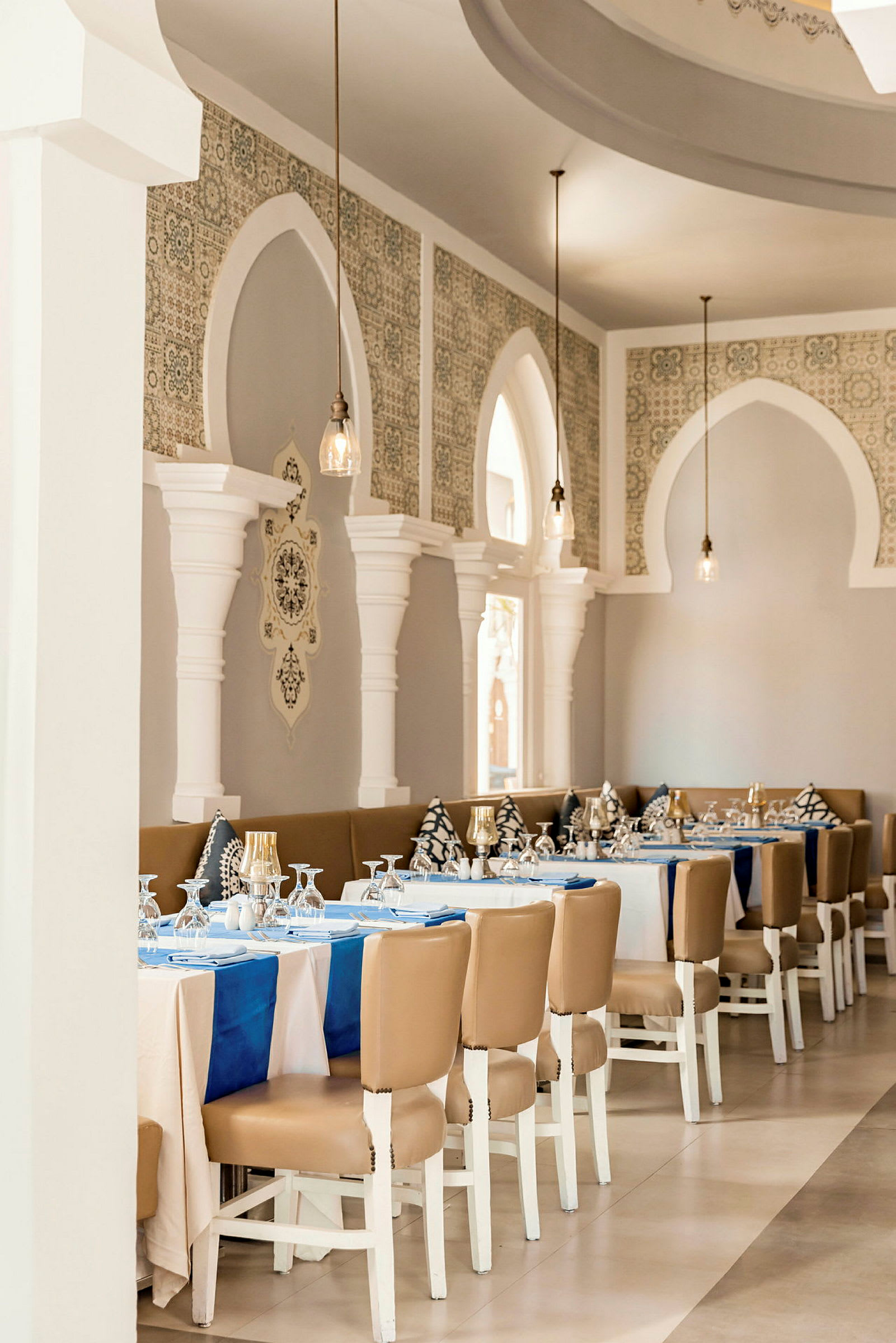 En elegant restaurant med dækkede borde, hvide vægge og dekorative buer. (AI-genereret tekst)