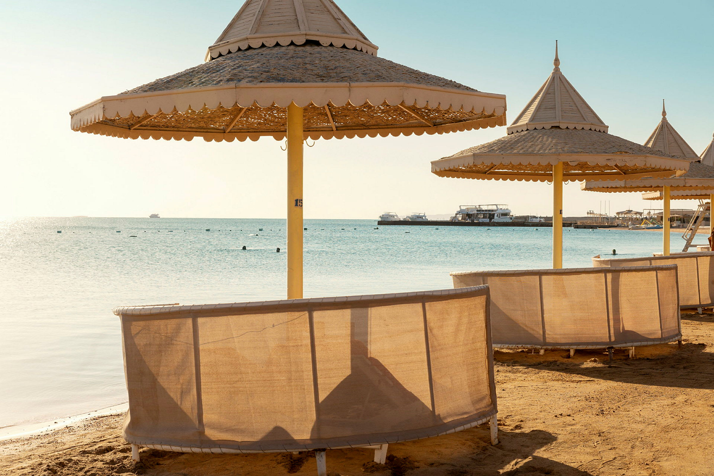 Parasolles står opstillet på en strand tæt ved havet. (AI-genereret tekst)