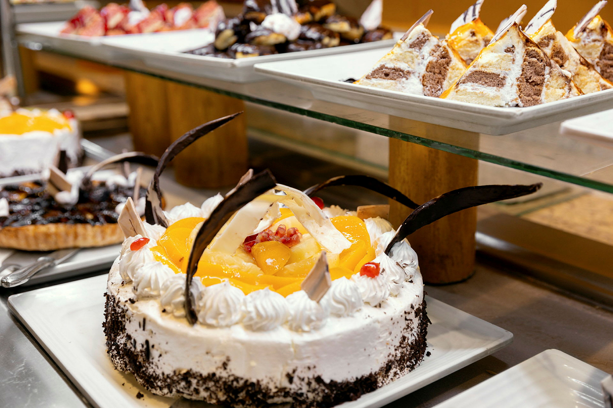 En lækker dessertbuffet med en dekoreret lagkage med frugt og chokolade i centrum. (AI-genereret tekst)