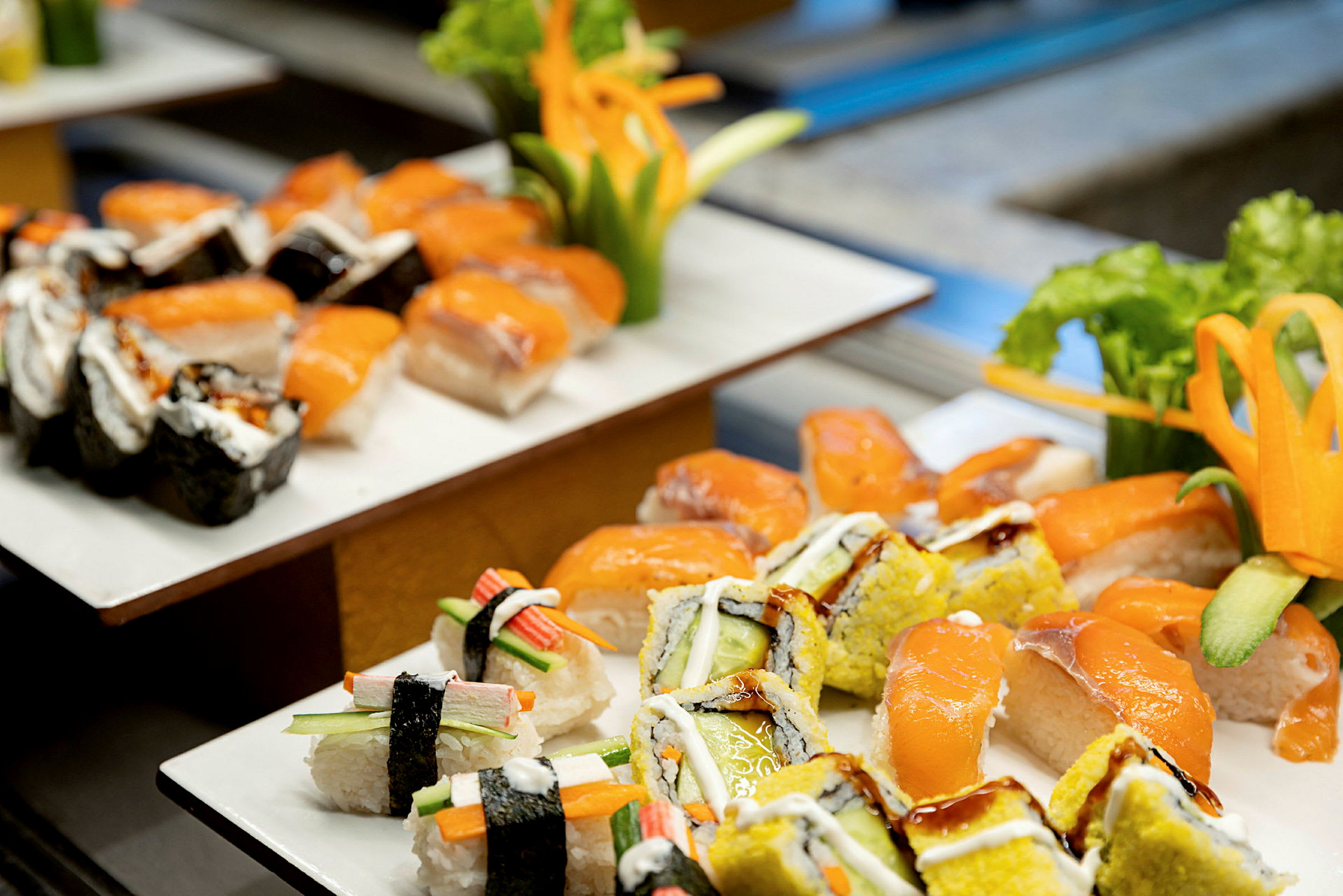 En tallerken med forskellige typer sushi, herunder nigiri med laks og makiruller, dekoreret med friske grøntsager. (AI-genereret tekst)