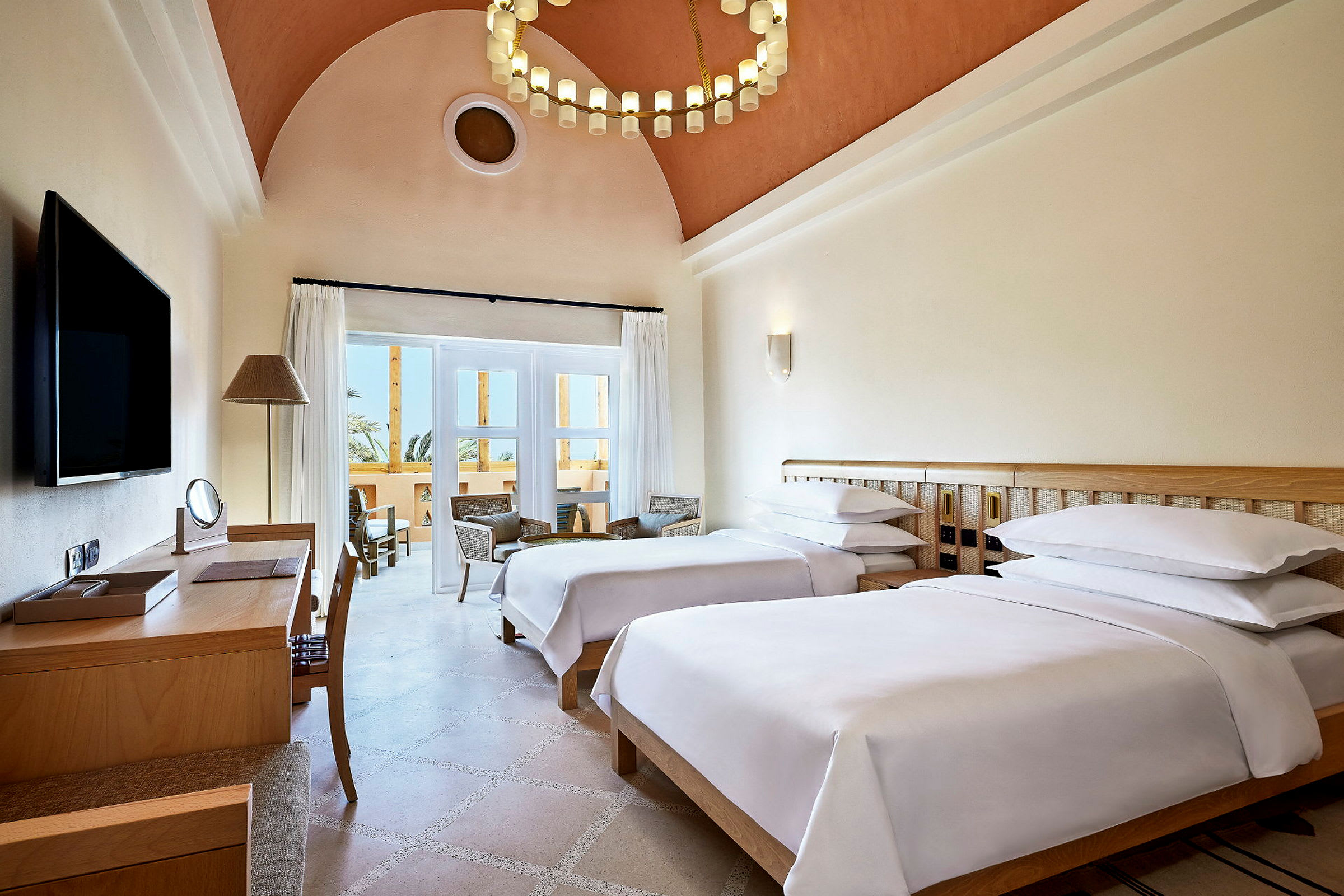 Hotelværelse med to enkeltsenge, skrivebord og siddeområde ved altanen. (AI-genereret tekst)