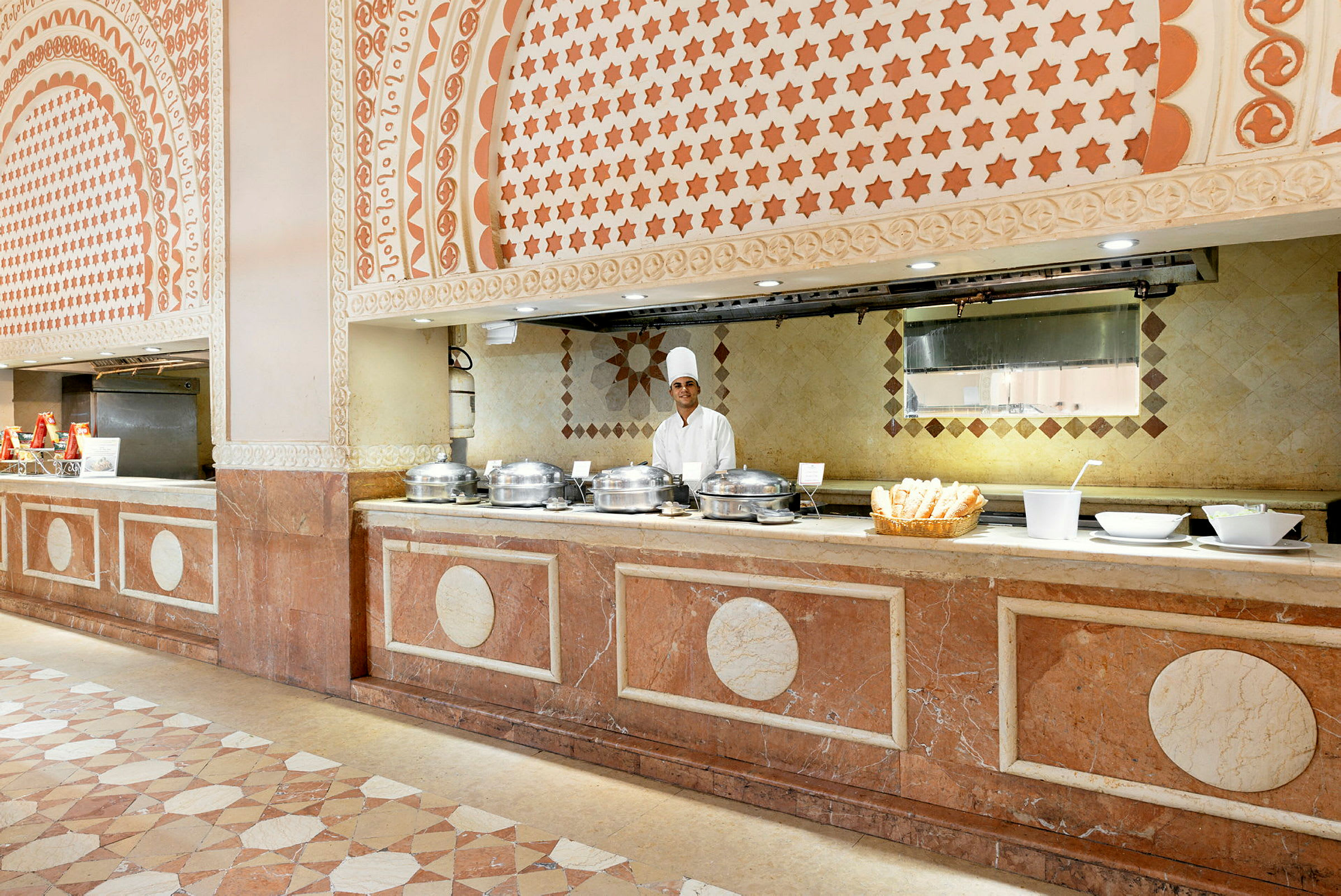 En buffet med mad i serveringsfade under dekorative hvælvinger og mønstre. (AI-genereret tekst)