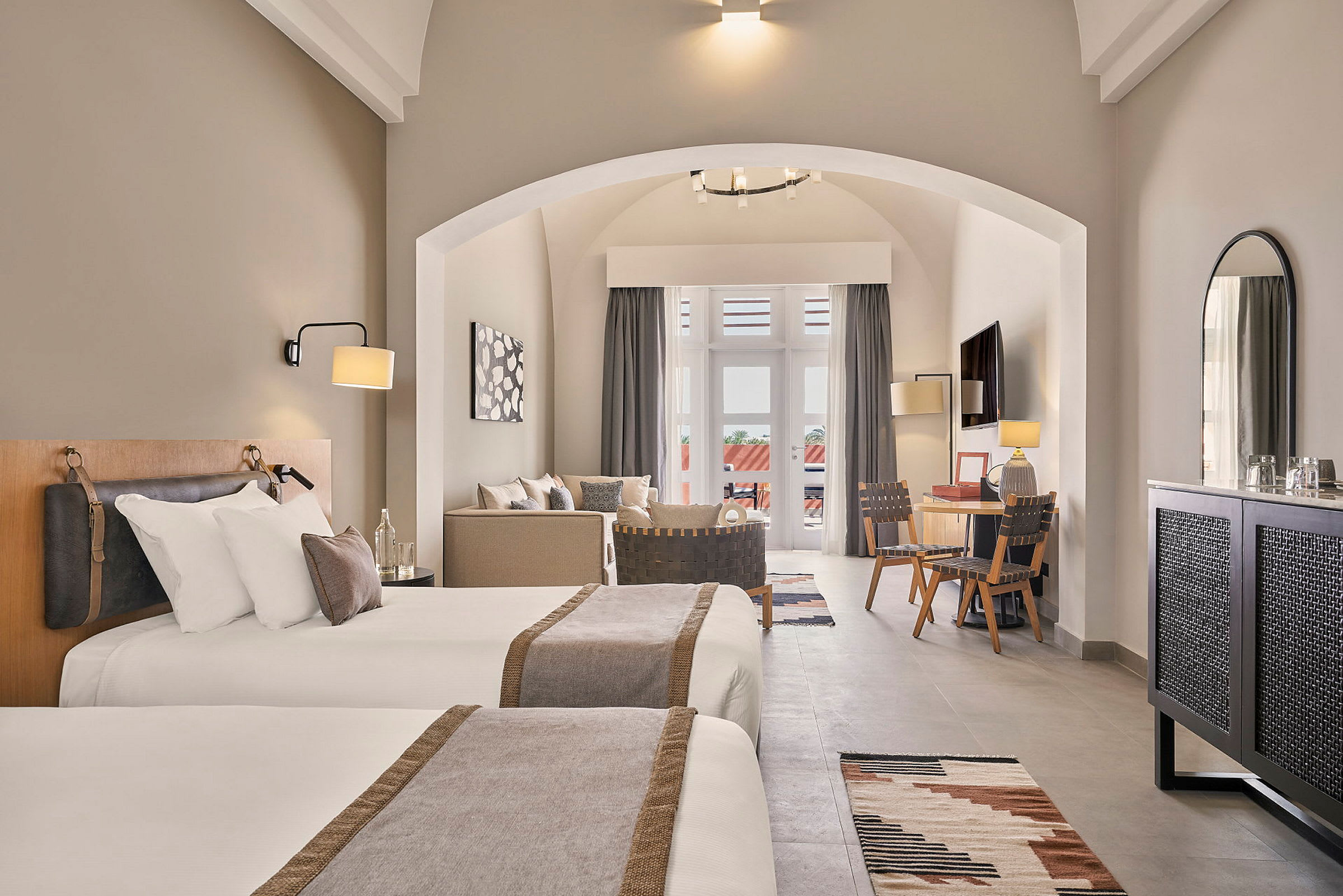 Hotelværelse med to enkeltsenge, siddeområde, skrivebord og altan. (AI-genereret tekst)