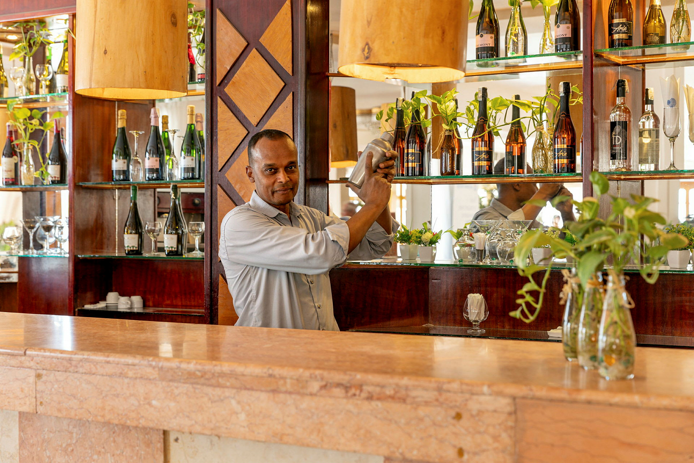 En bartender ryster en cocktail bag en bardisk med flasker og dekorationer. (AI-genereret tekst)