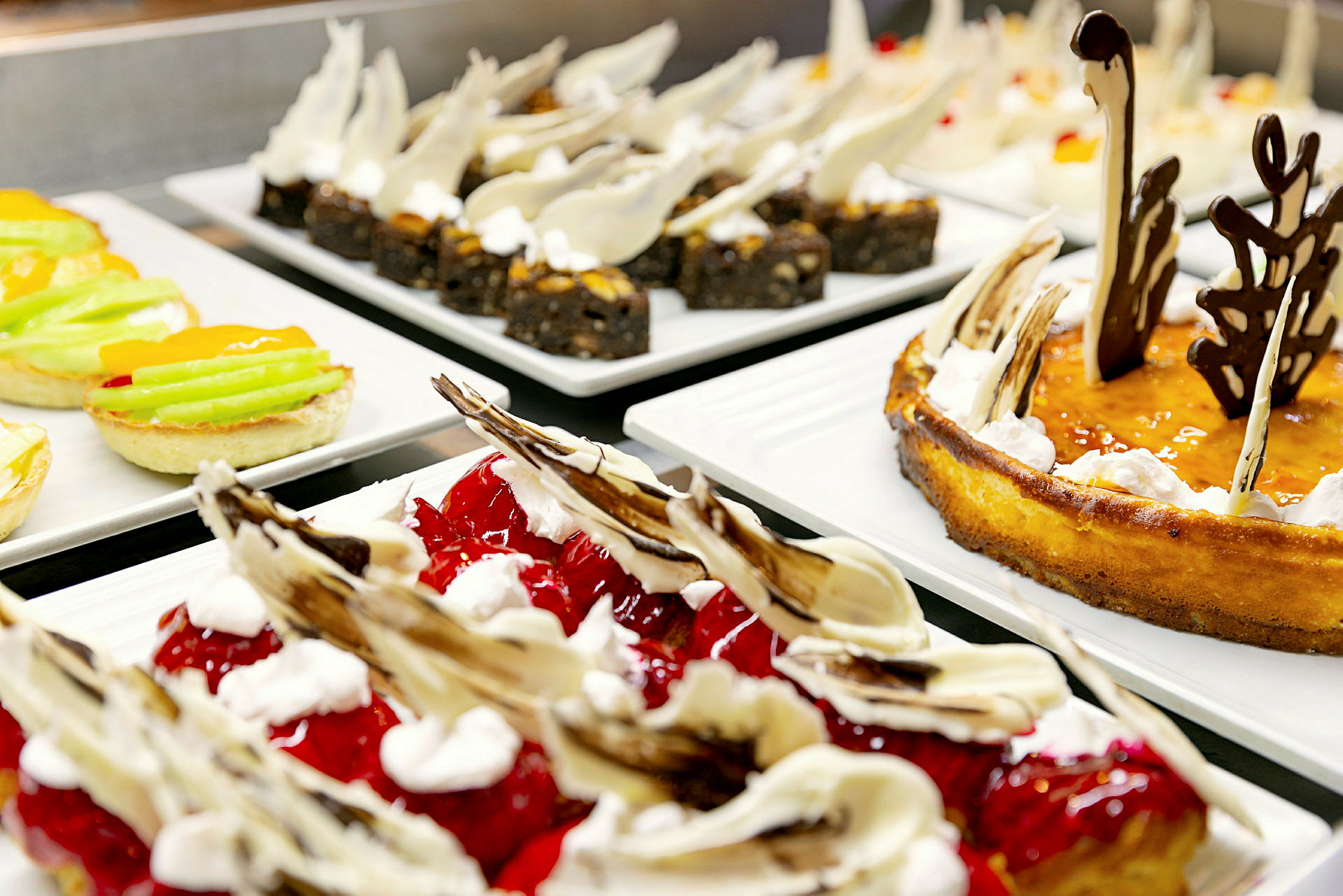 Billede af forskellige desserter anrettet på tallerkener på en buffet. (AI-genereret tekst)