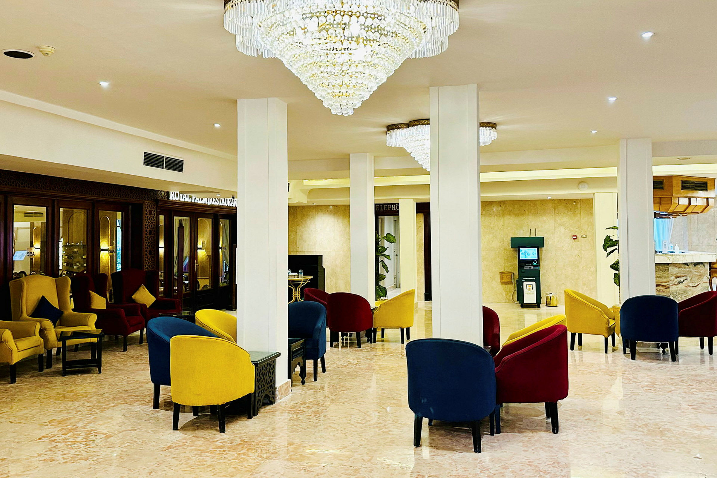 Et elegant hotellets lobbyområde med farverige stole og imponerende lysekroner. (AI-genereret tekst)