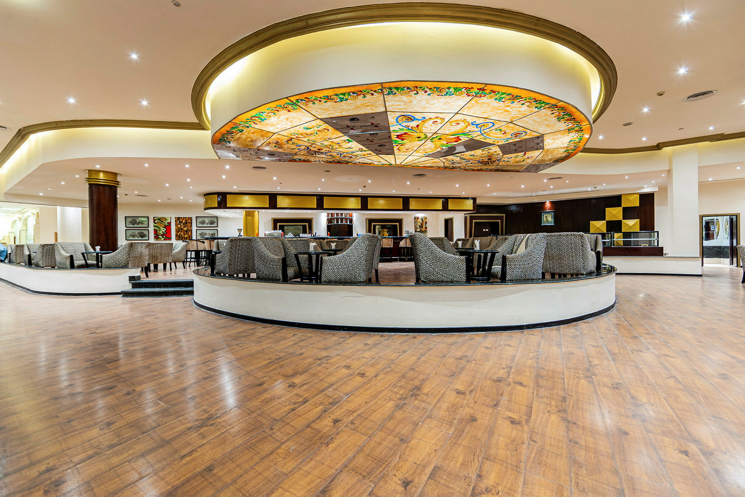 En rummelig hotellobby med dekorativt loft og siddegrupper. (AI-genereret tekst)