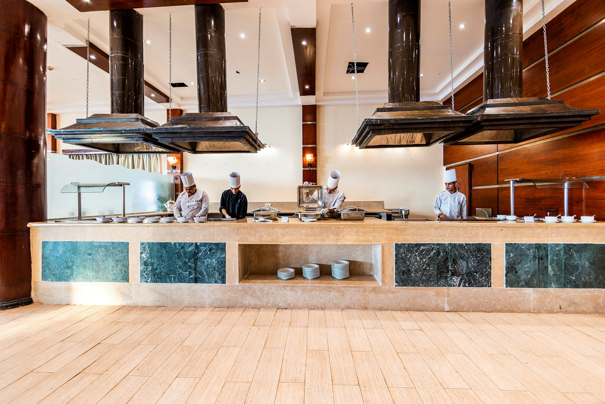 En hotelrestaurant med en buffetskranke og køkkenudstyr under store emhætter. (AI-genereret tekst)