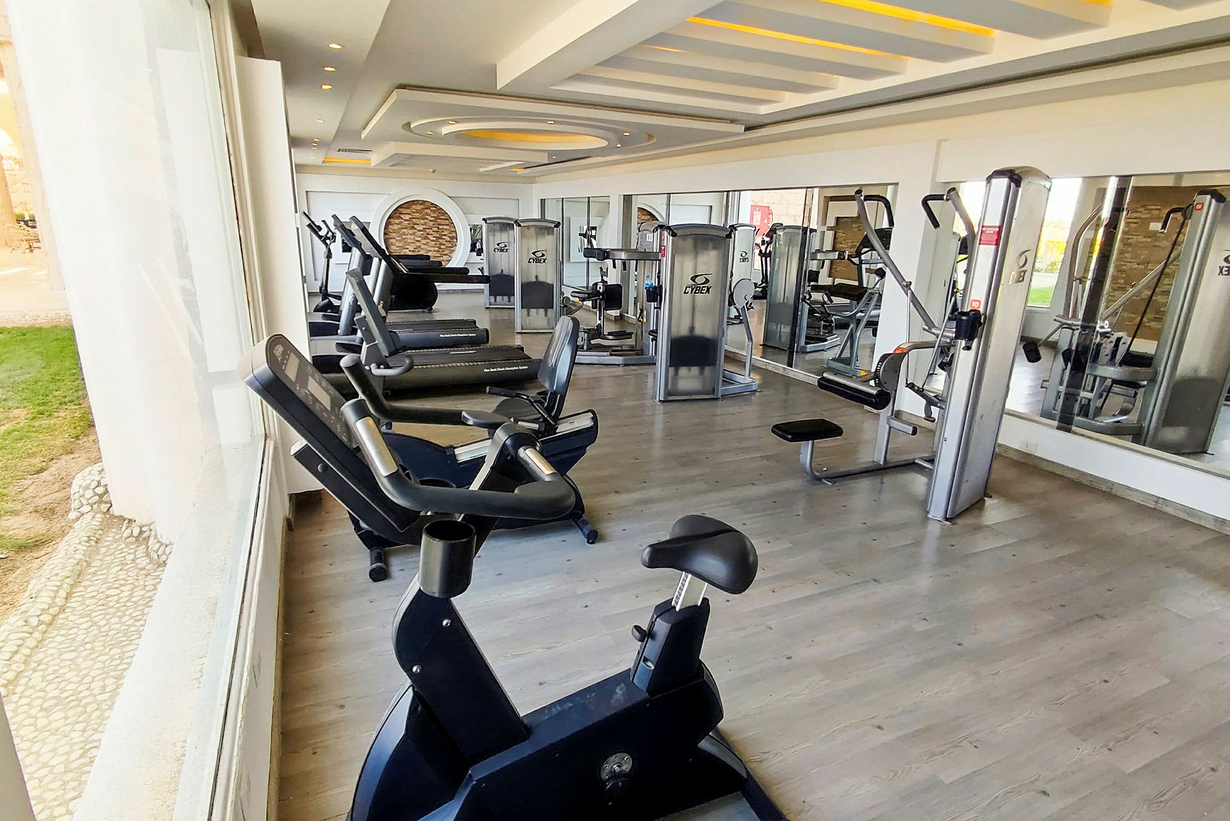 Billede af et fitnesscenter med forskellige træningsmaskiner og spejlvægge. (AI-genereret tekst)