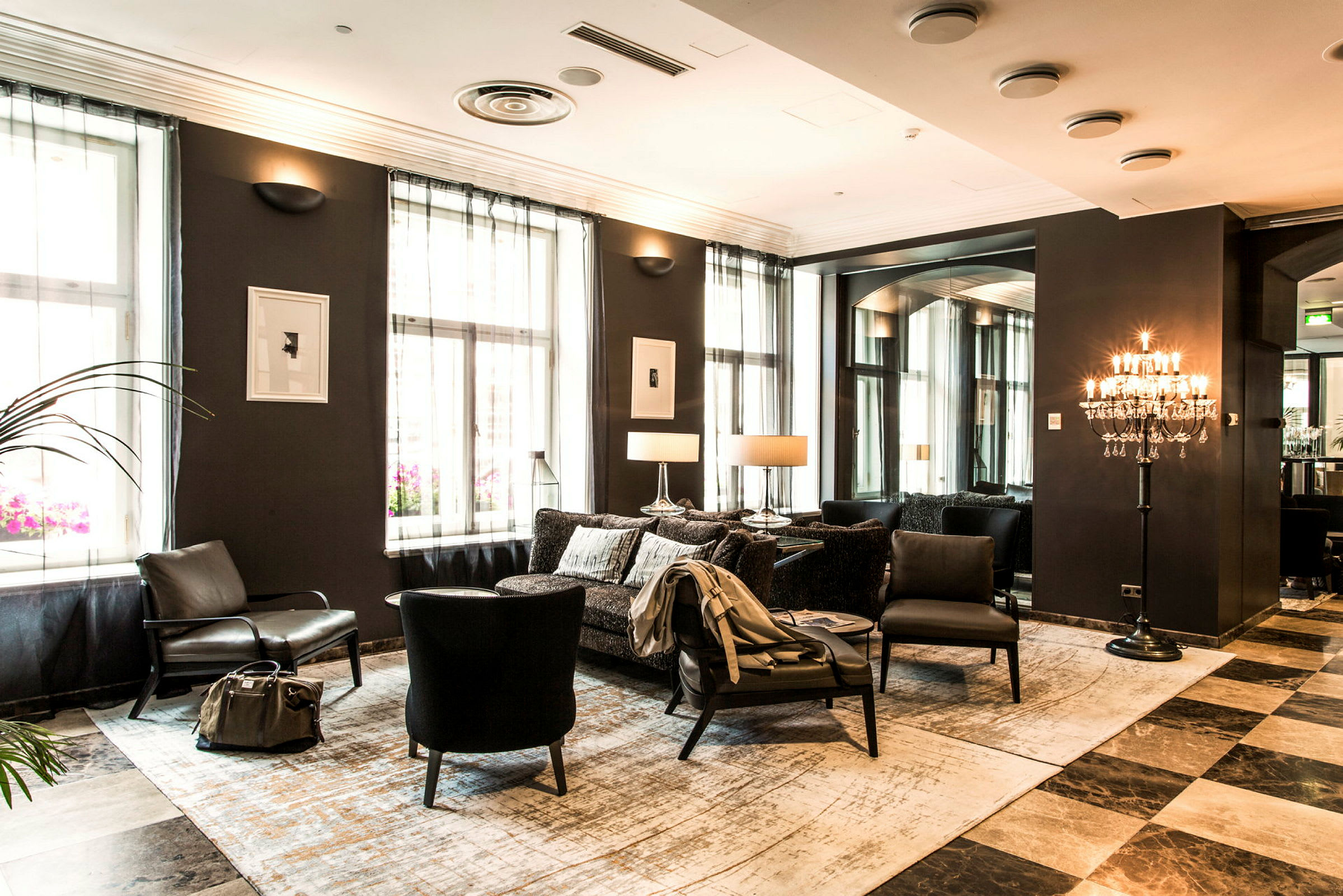 Et elegant hotelværelse med siddepladser, væglamper og vinduer med lyse gardiner. (AI-genereret tekst)