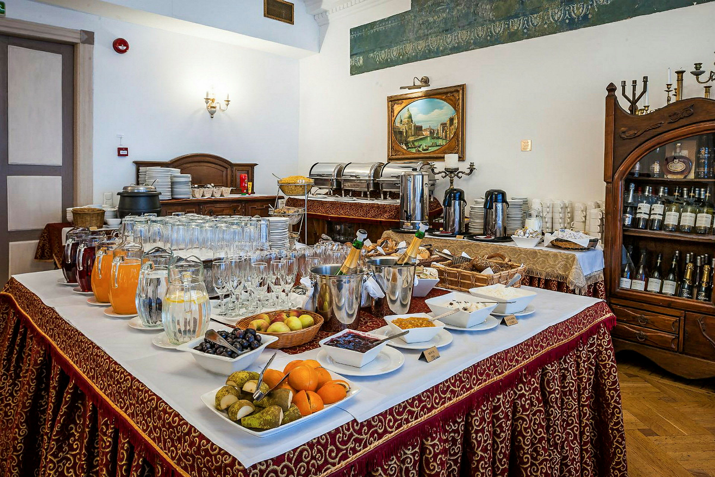 Et buffetbord med forskellige drikkevarer, frugter og småretter opstillet i en elegant restaurant. (AI-genereret tekst)