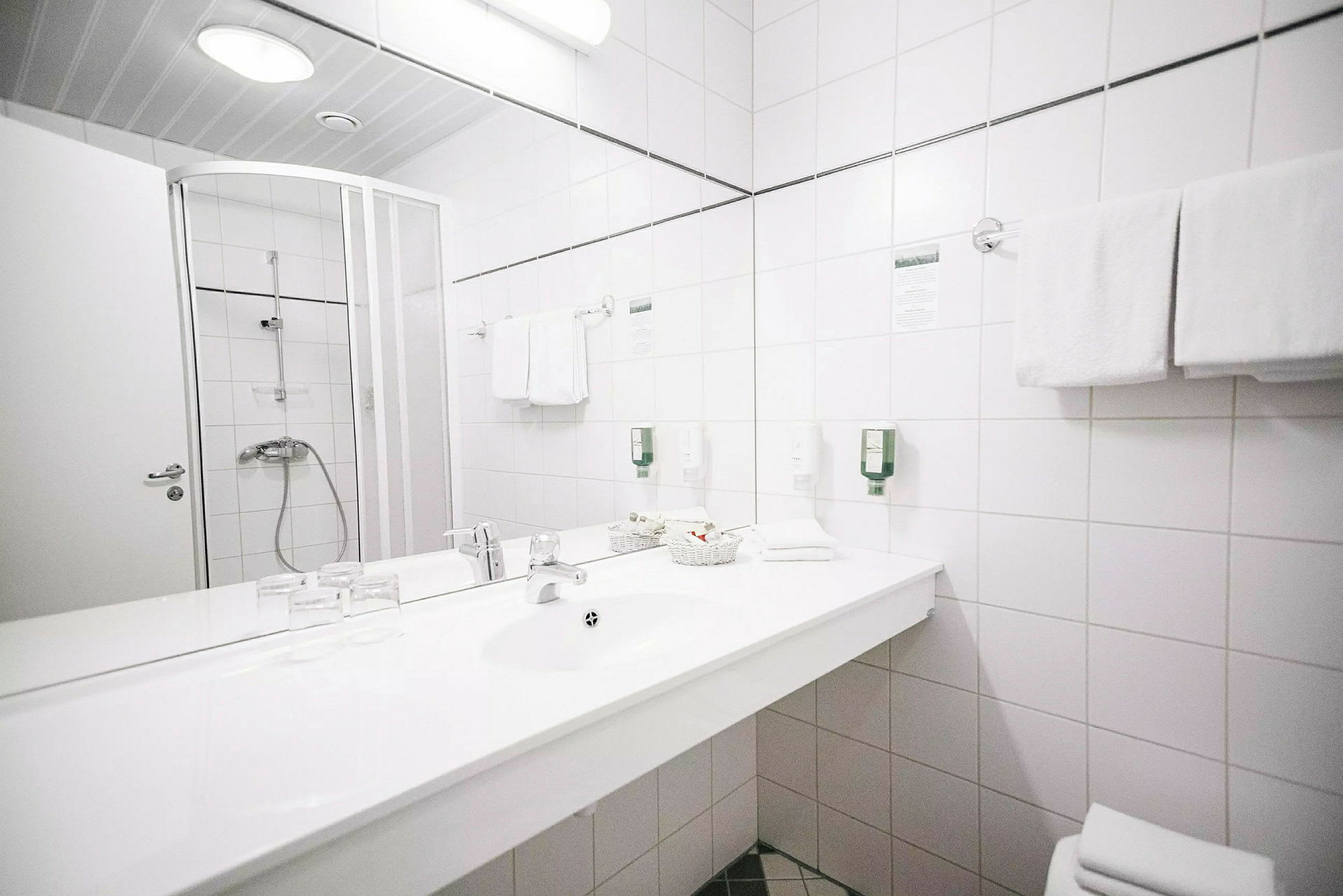 Badeværelse med brusekabine, håndvask og spejl. (AI-genereret tekst)
