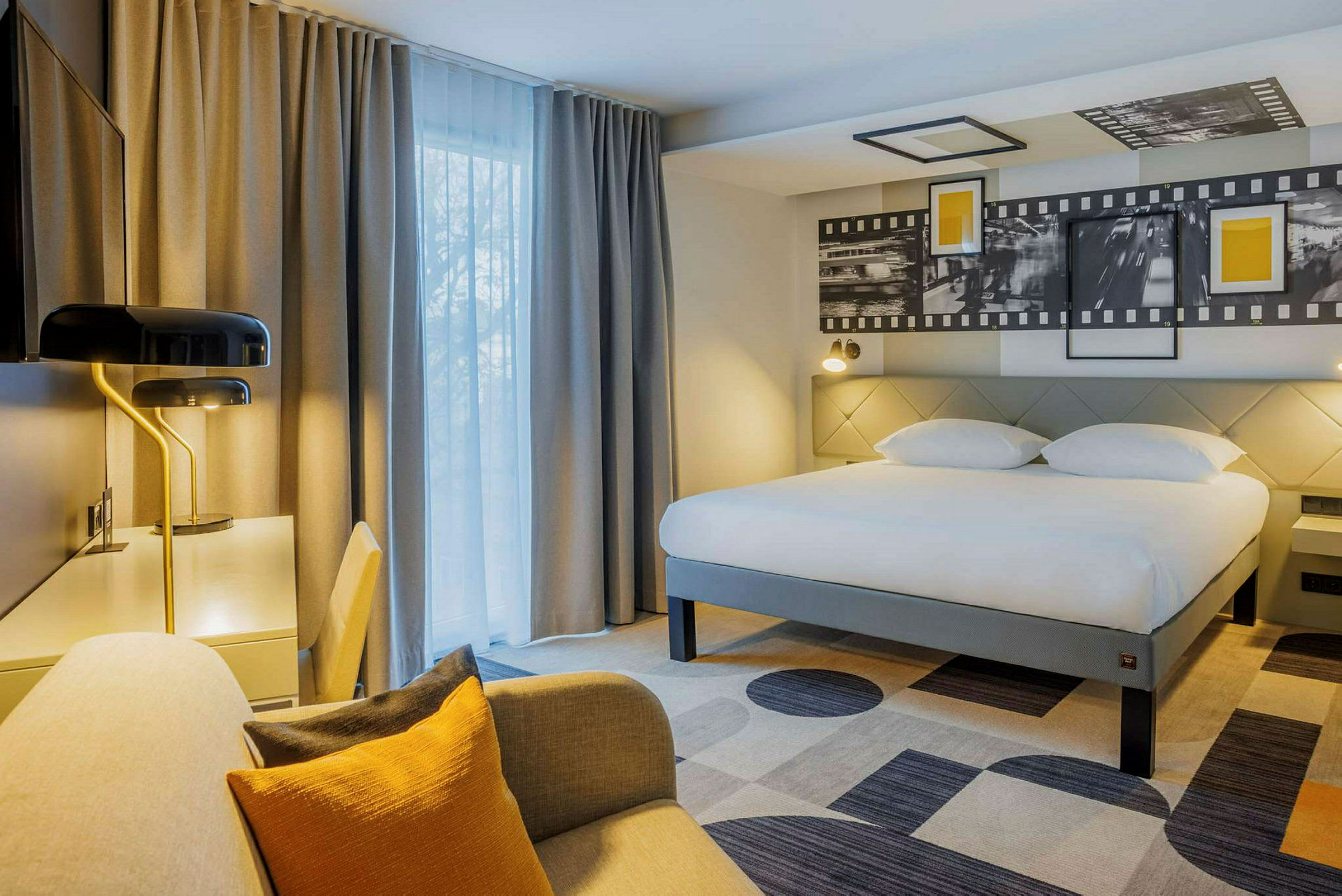 Hotelværelse med stor seng, skrivebord og siddeområde. (AI-genereret tekst)