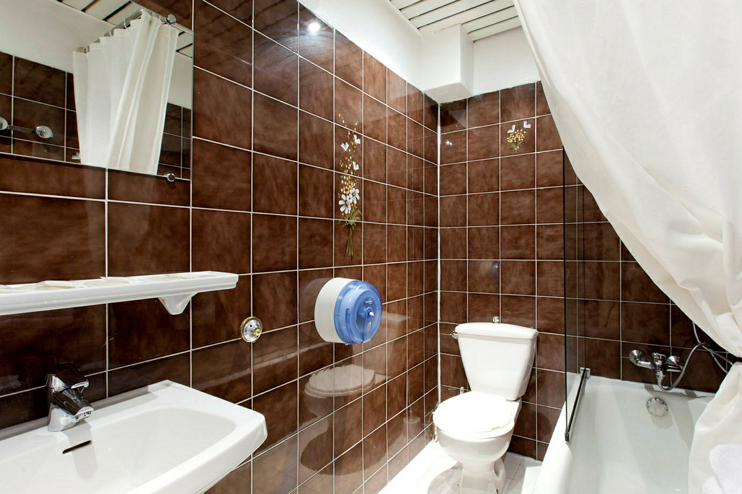 Badeværelse med brune fliser, toilet, håndvask og badekar. (AI-genereret tekst)