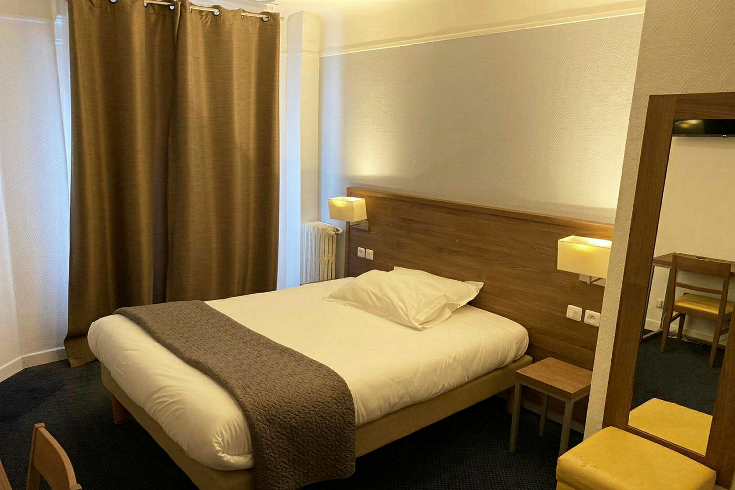 Hotelværelse med en dobbeltseng, natbord og skrivebord. (AI-genereret tekst)