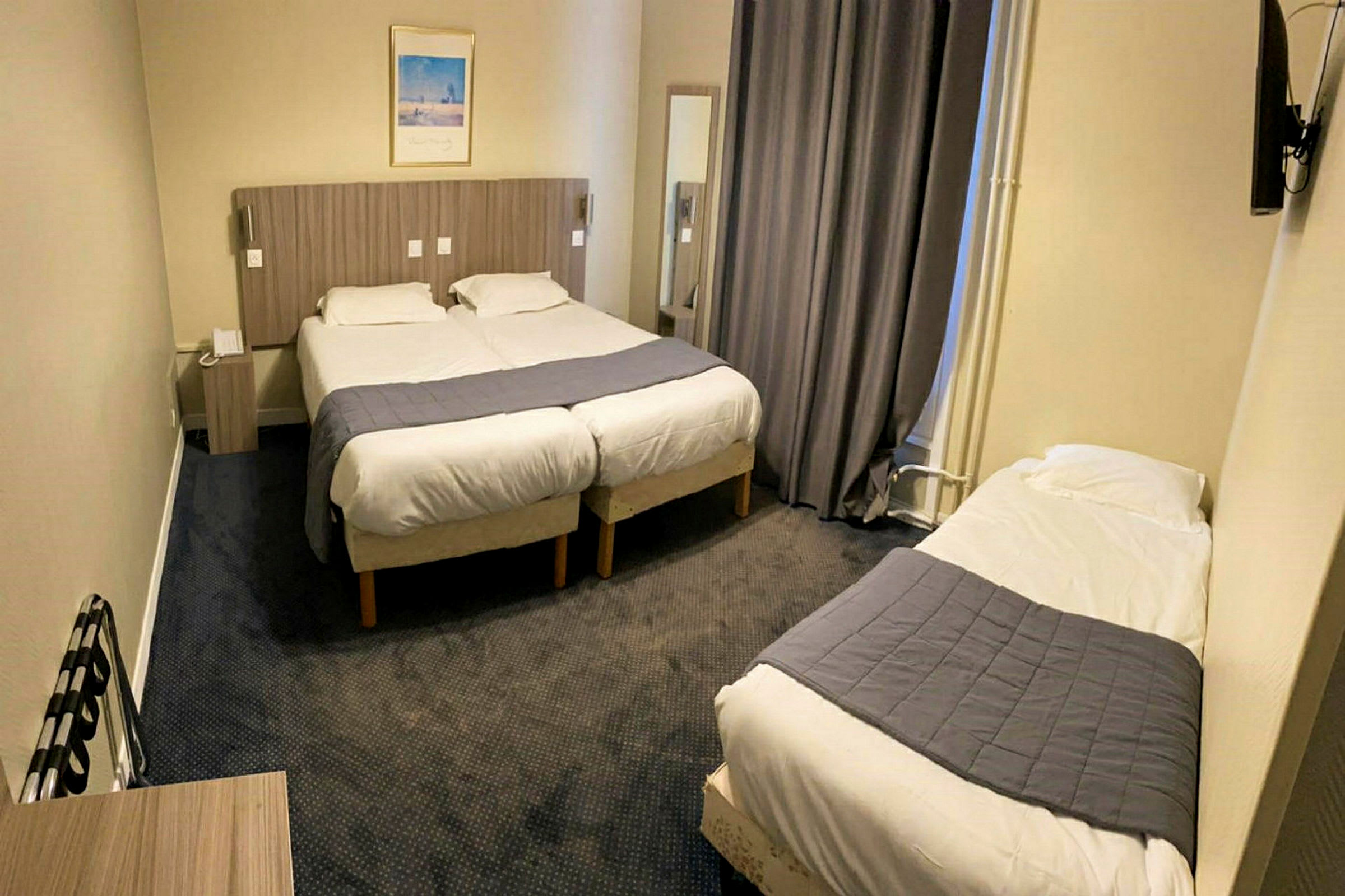 Et hotelværelse med to enkeltsenge sammenstillet og en separat enkeltseng. (AI-genereret tekst)
