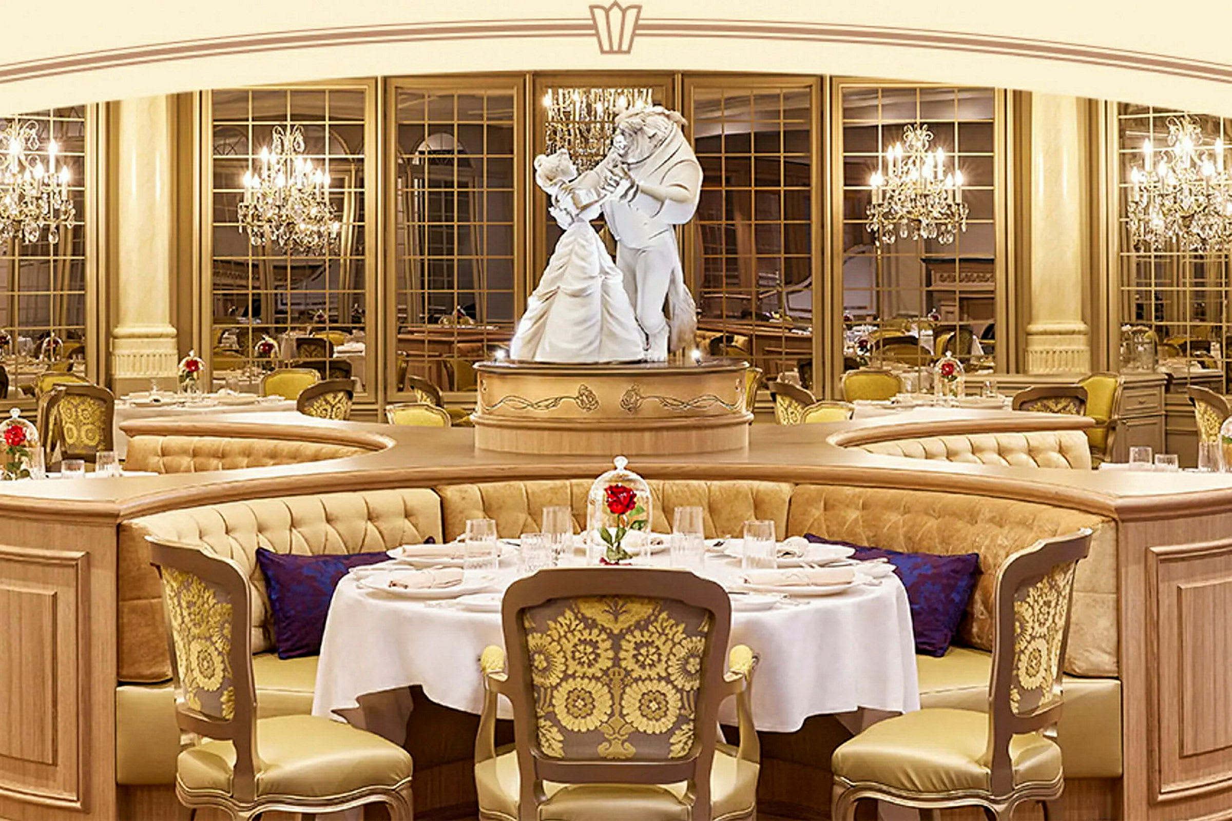 Et billede af en elegant restaurant med luksuriøse møbler og en statue, der viser to dansende figurer i centrum. Bordene er dekoreret med hvide duge og røde blomster i glaskupler. (AI-genereret tekst)