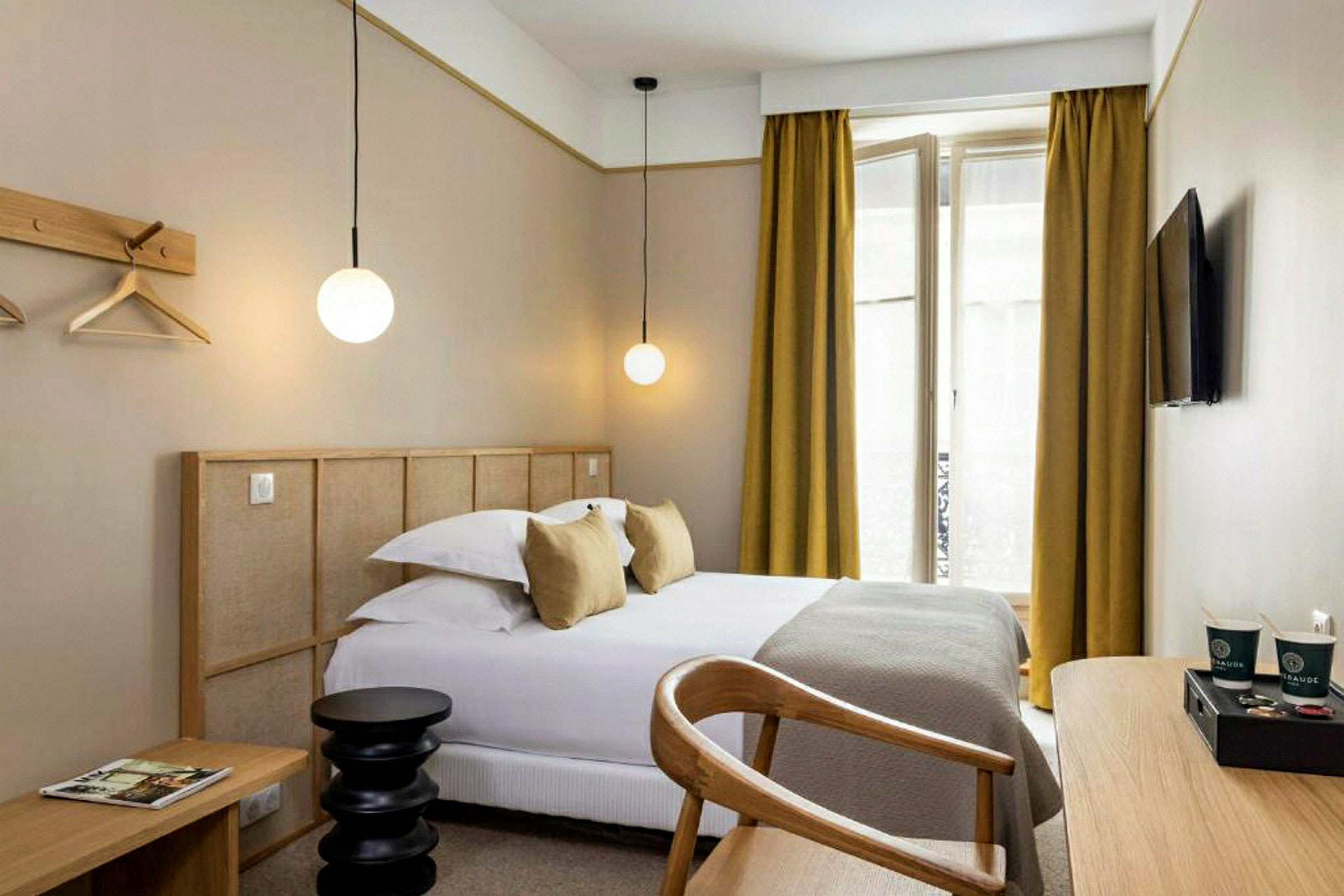 Et moderne hotelværelse med en seng, skrivebord og et tv på væggen. (AI-genereret tekst)