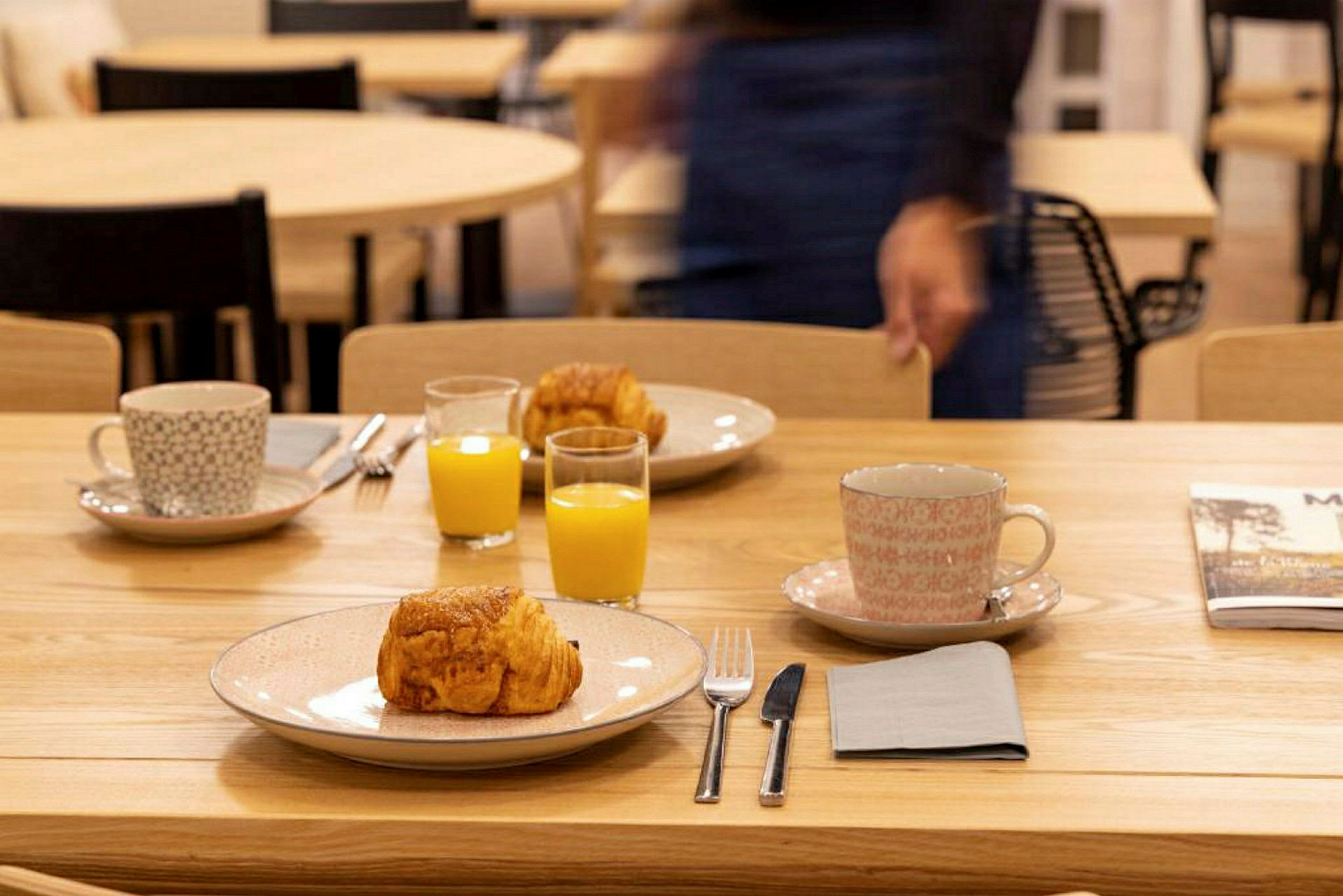 Et bord dækket med tallerkener, croissanter, kopper og glas med appelsinjuice. (AI-genereret tekst)