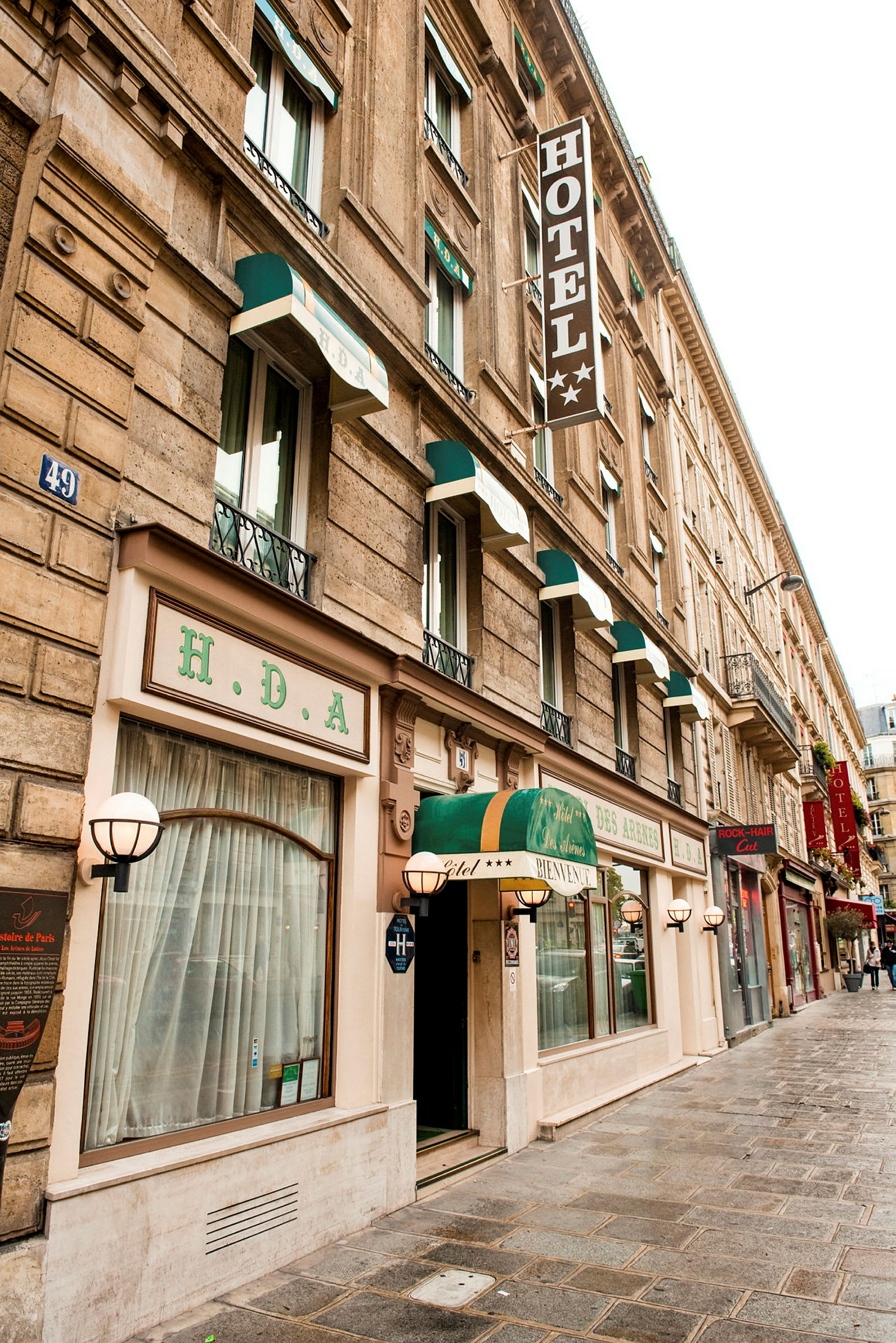 Hotellets facade med flere vinduer og et skilt med teksten 'HOTEL'. (AI-genereret tekst)