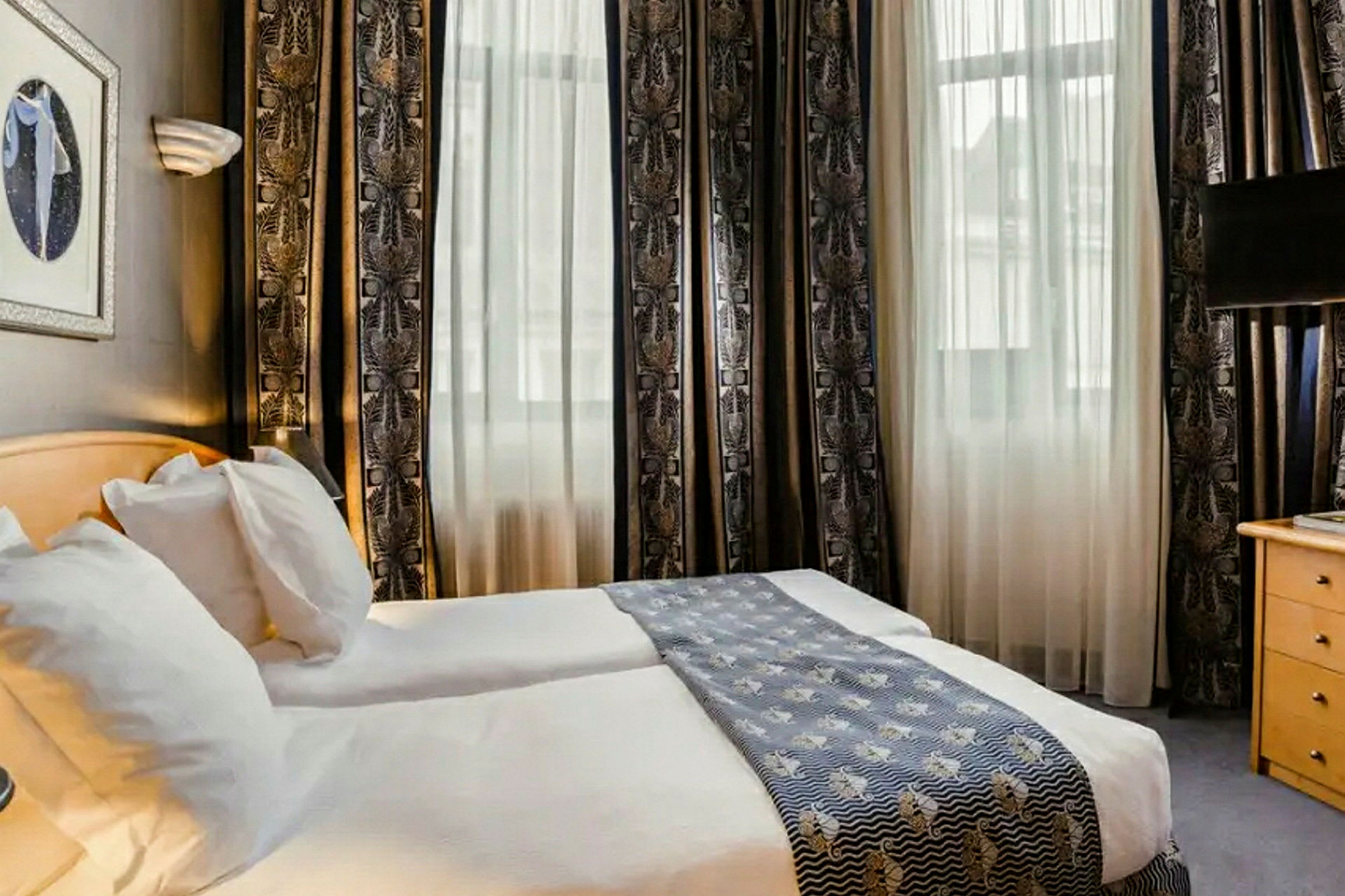 Et hotelværelse med to enkeltsenge, lyse gardiner og en dekorativ sengeløber. (AI-genereret tekst)
