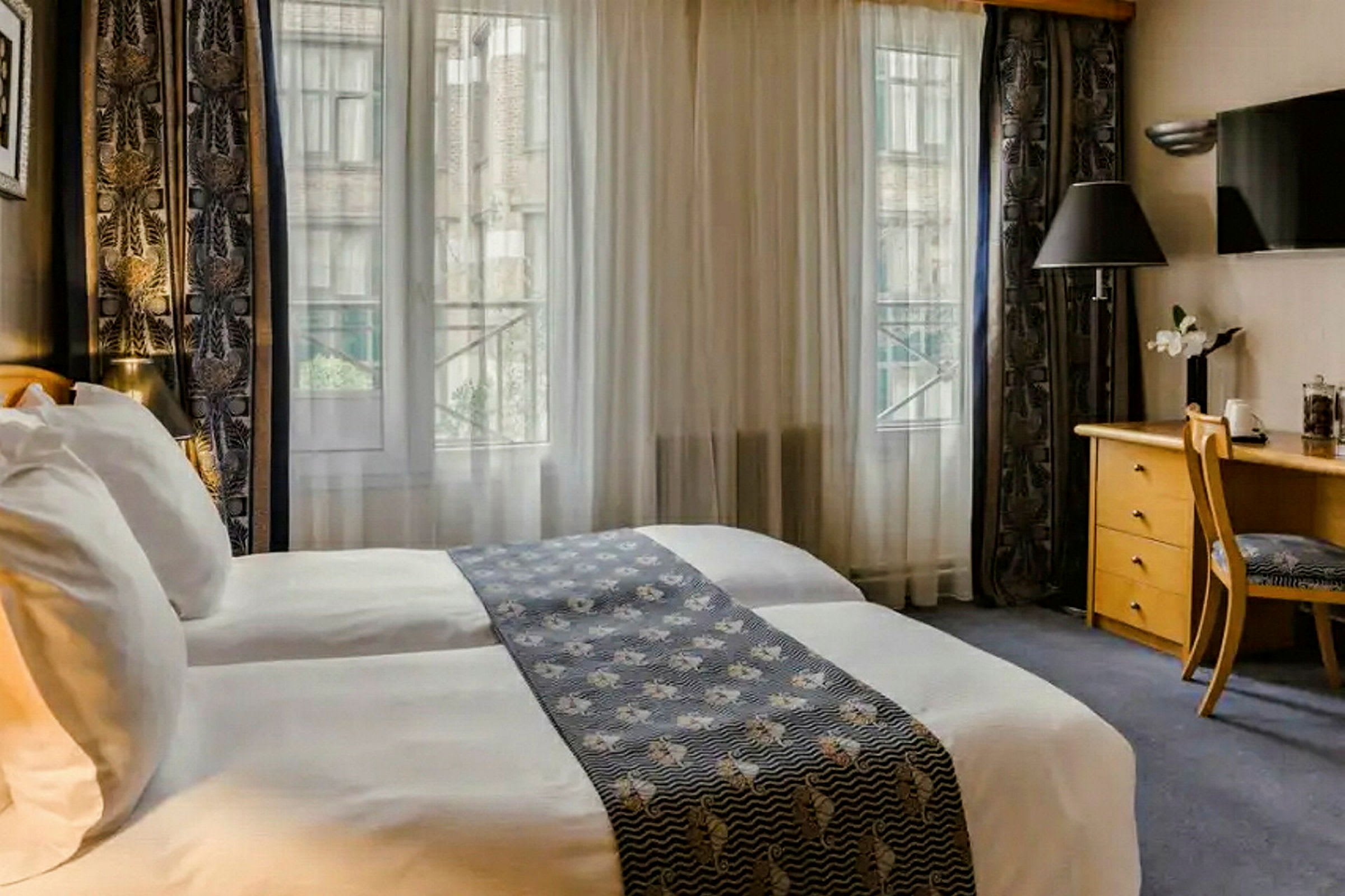Hotelværelse med to senge, skrivebord og vindue med udsigt. (AI-genereret tekst)