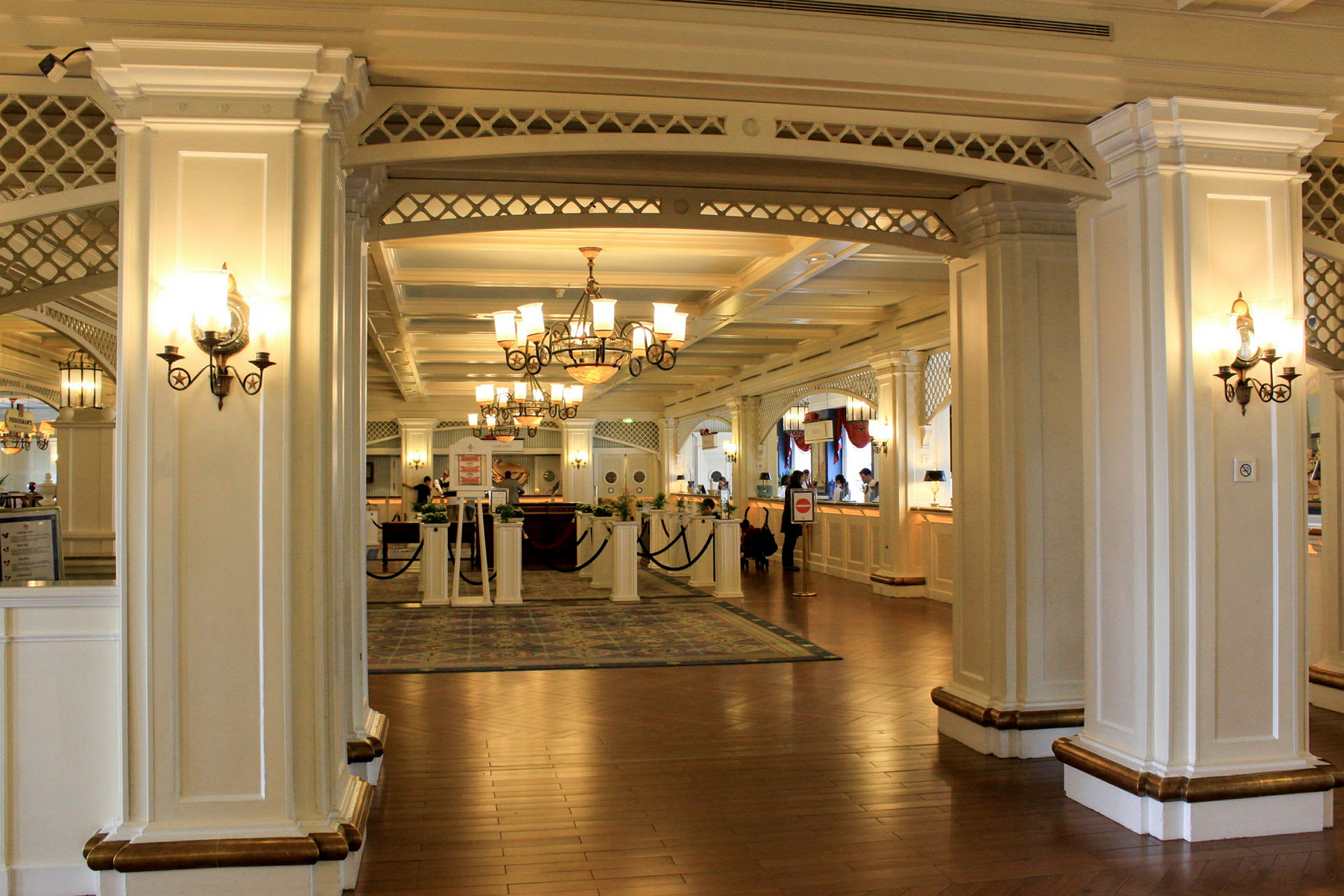 En elegant hotellobby med hvide søjler, lysekroner og receptionen. (AI-genereret tekst)