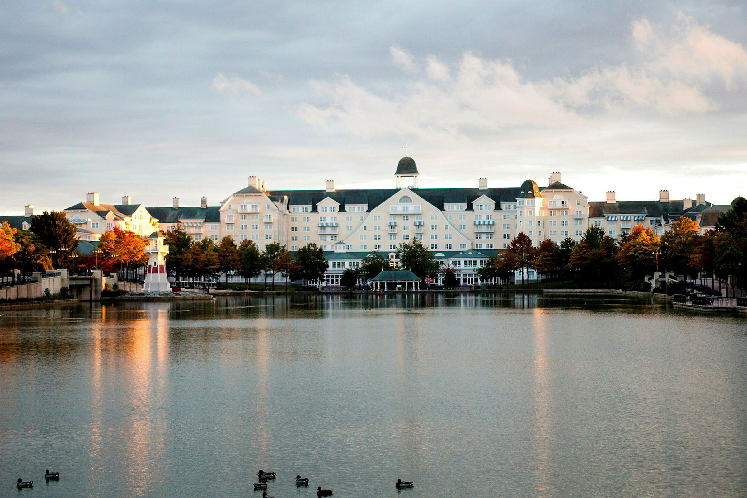 Hotelbygning ved en sø med et lille fyrtårn. (AI-genereret tekst)