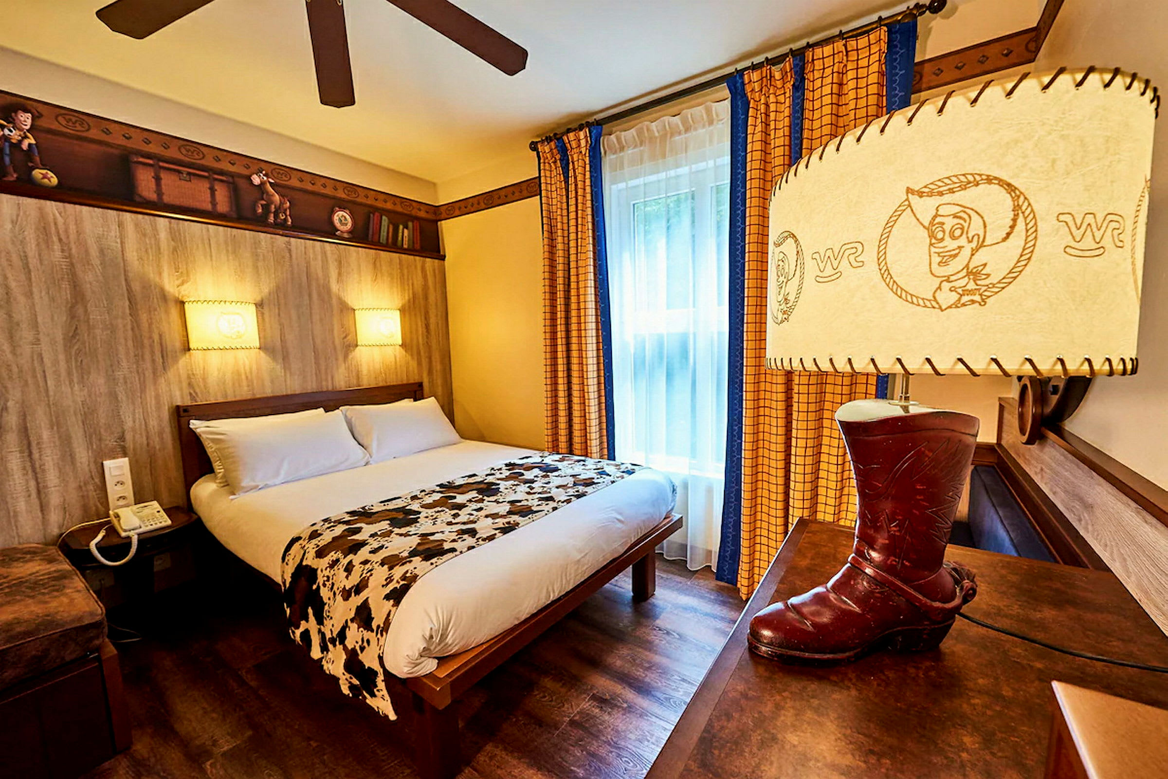 Et tematiseret hotelværelse med en dobbeltseng, dekoreret med legetøjsinspirerede detaljer og en lampe formet som en cowboystøvle. (AI-genereret tekst)